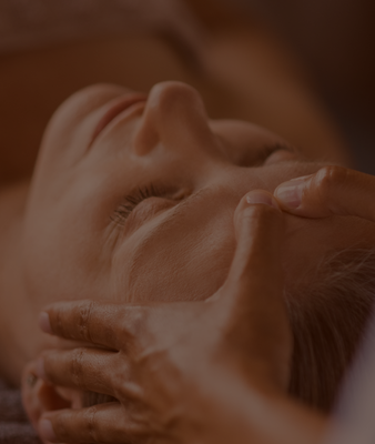 Close-up of a person receiving a facial massage with hands gently on their face.