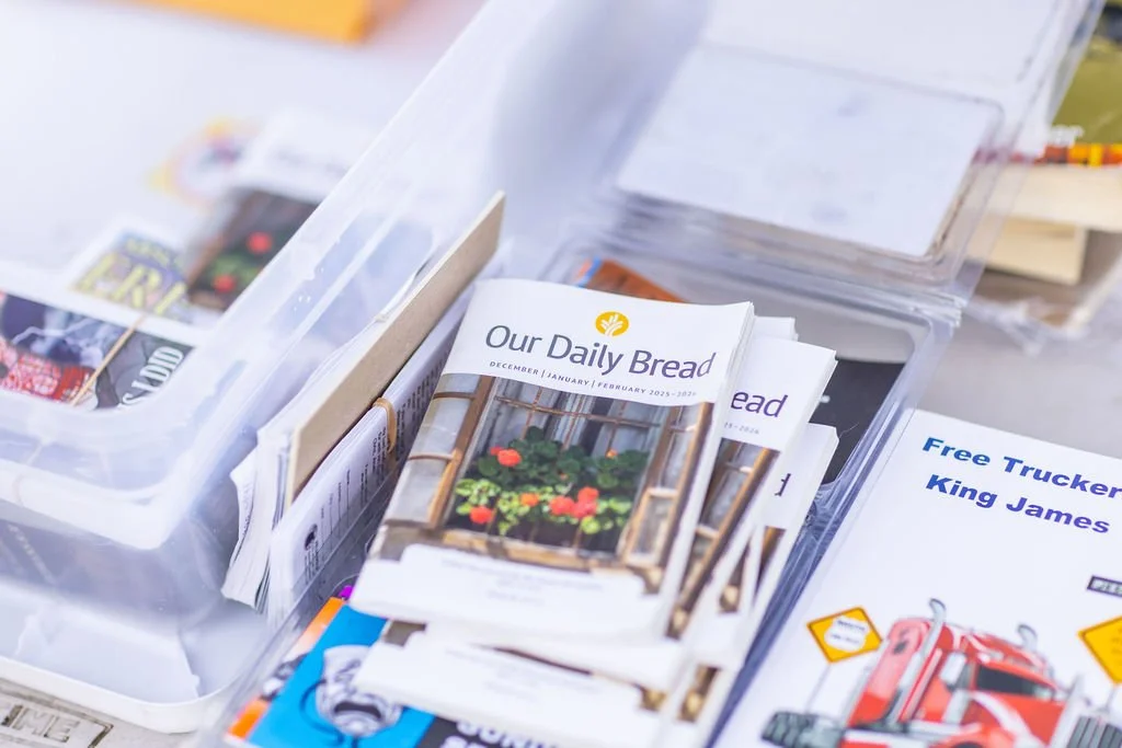 A stack of community newsletters titled "Our Daily Bread" with a picture of potted plants on the cover.