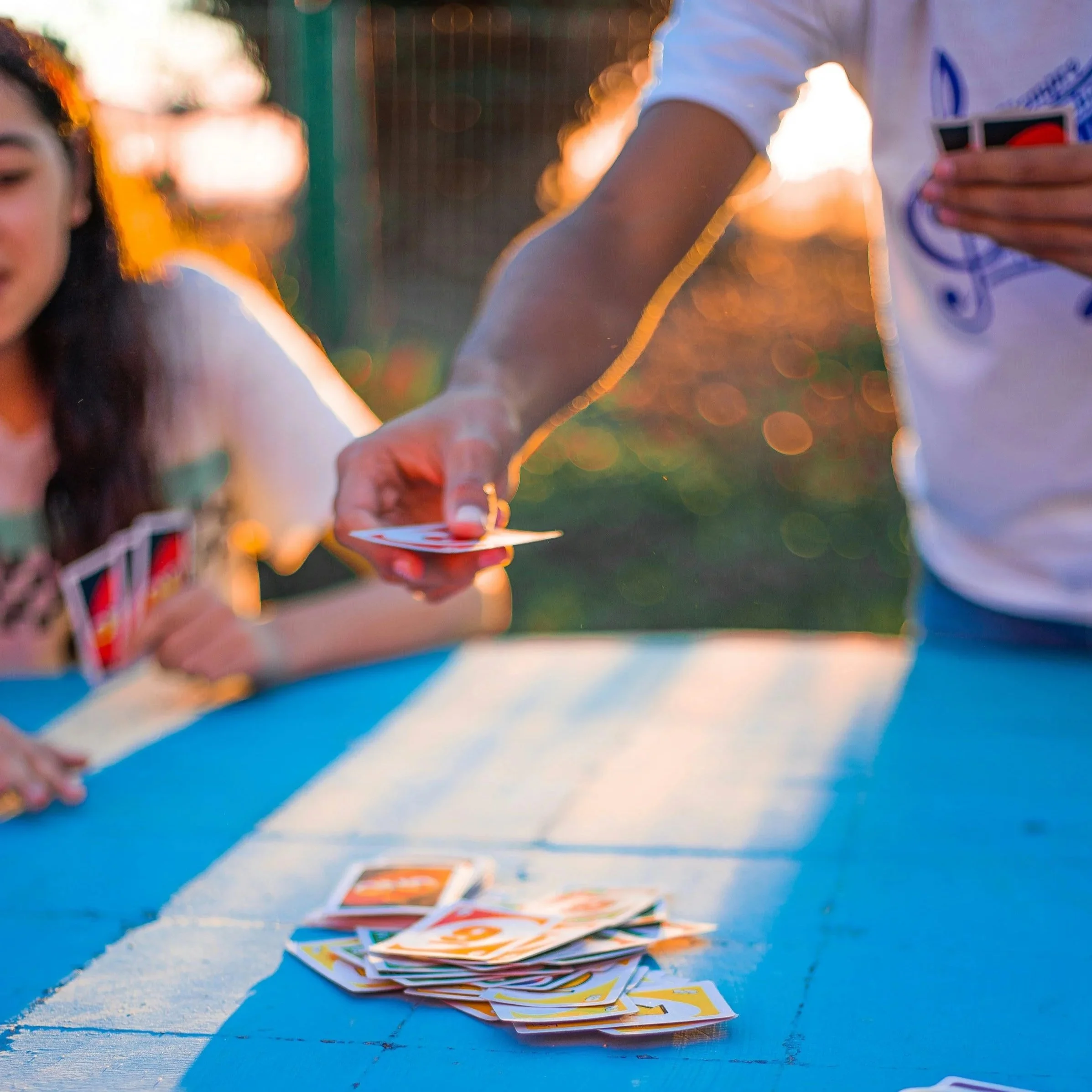 Family and friends playing a card game at a table in the evening sun