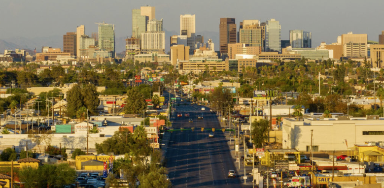 City skyline with tall buildings and a wide street in foreground during daytime.