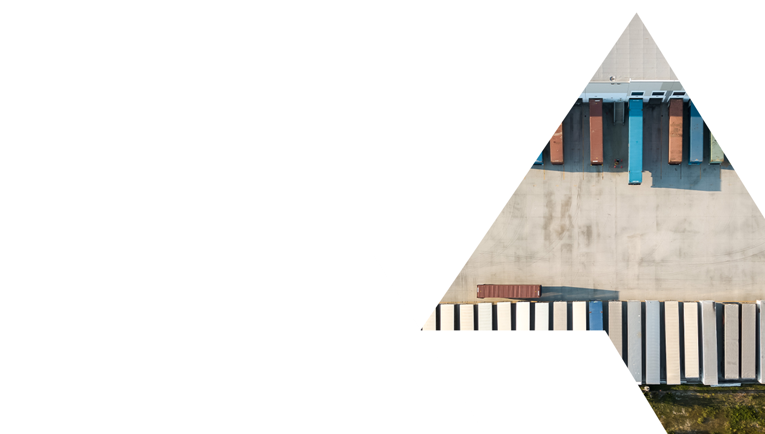 An aerial view of a parking lot with several shipping containers and trailers, with a building roof on top.