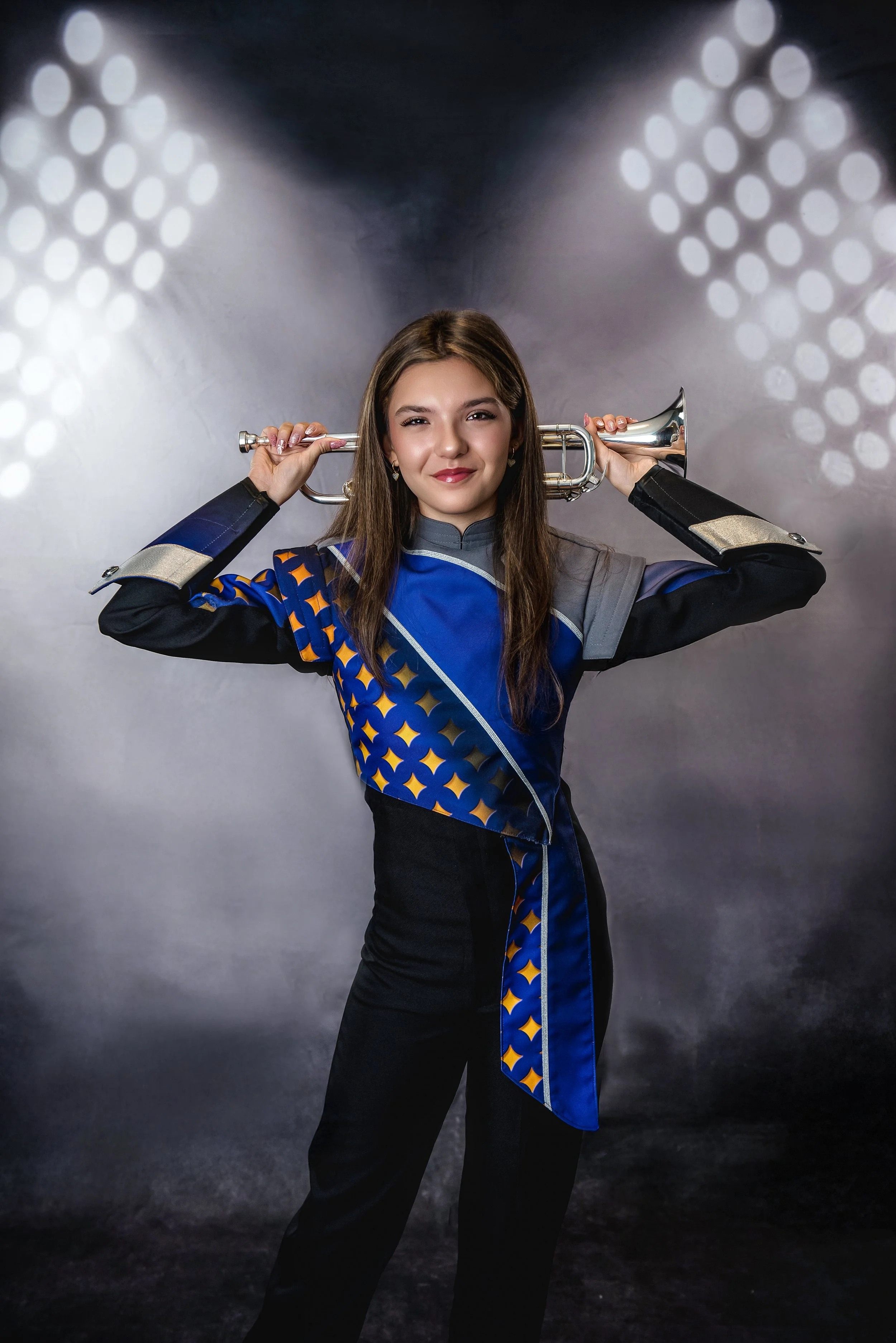 In our Spring Branch studio a young woman posing with a trumpet on her shoulders in a dark studio with bright light patterns.
