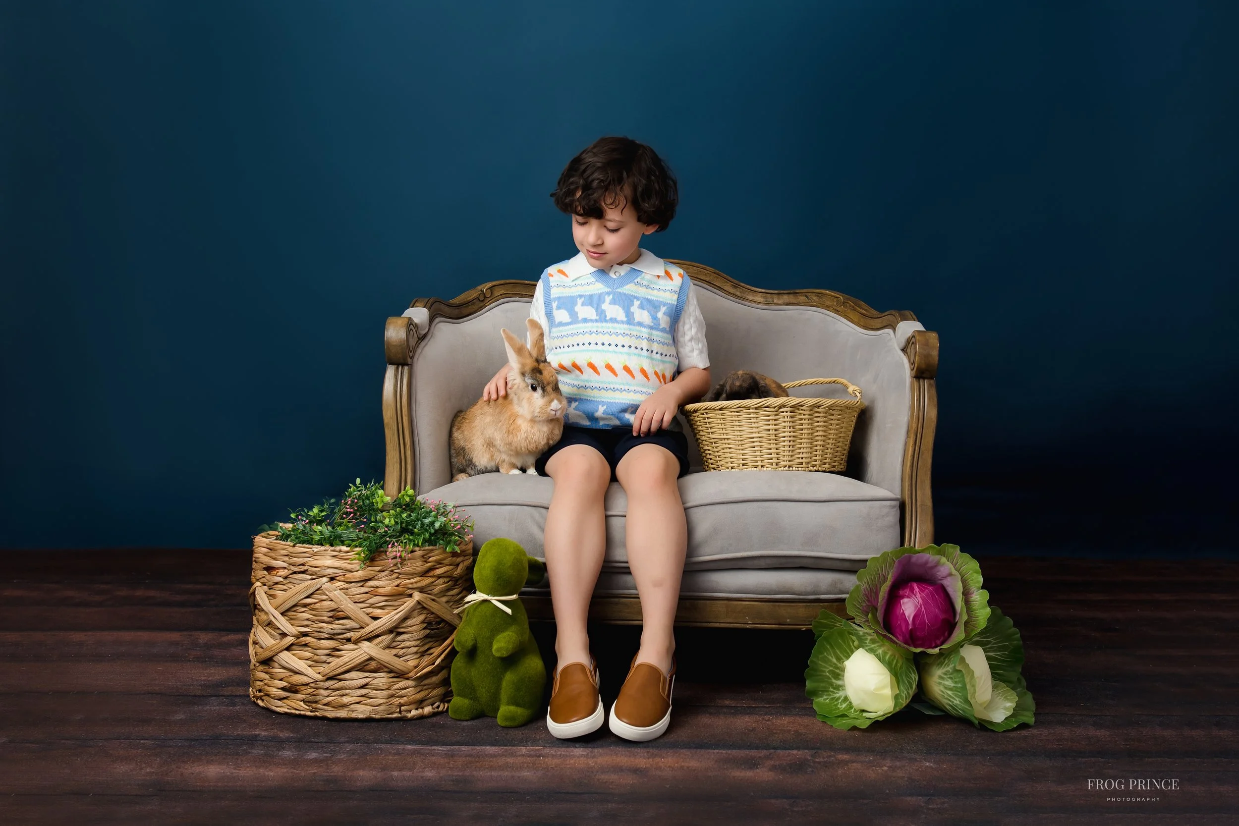 young boy gently hold bunnies while smiling during an studio-inspired spring bunny session in San Antonio.