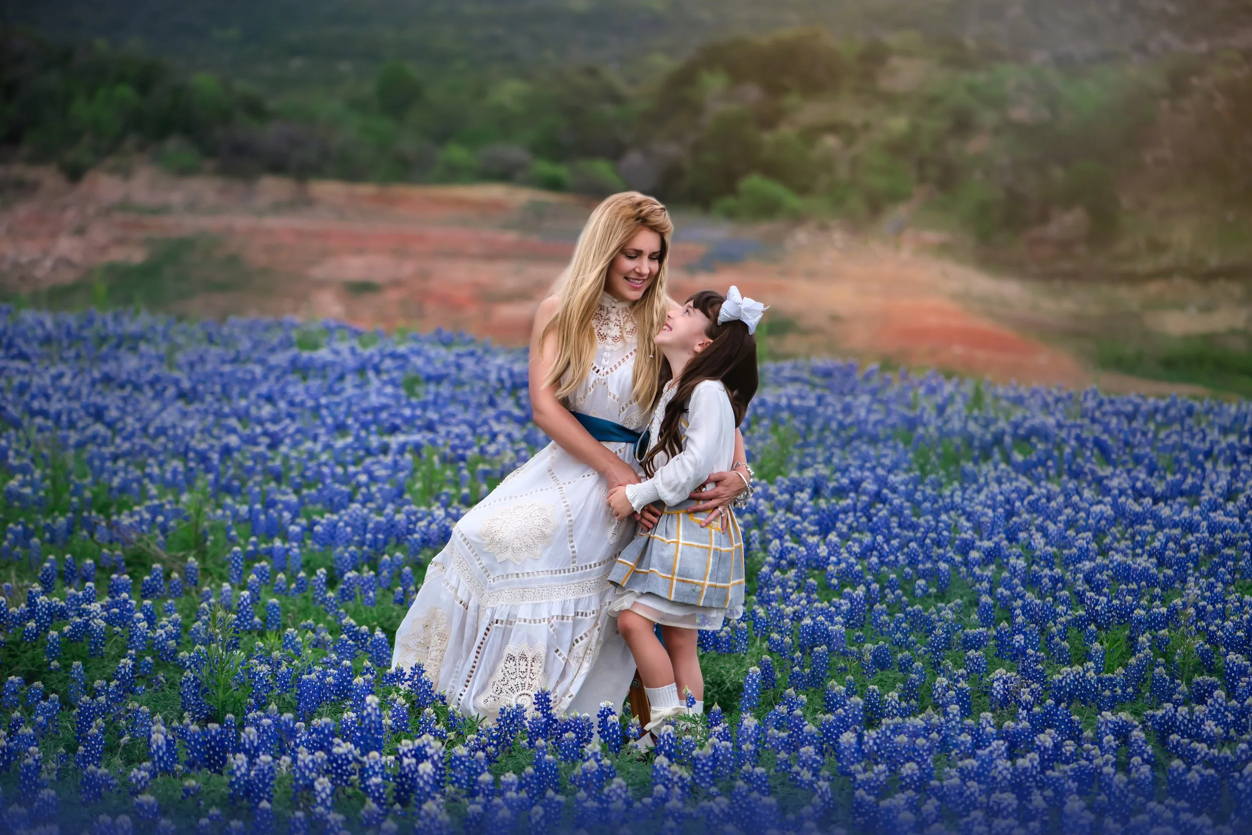 Mother holding her child during a bluebonnet portrait session in the Texas Hill Country.