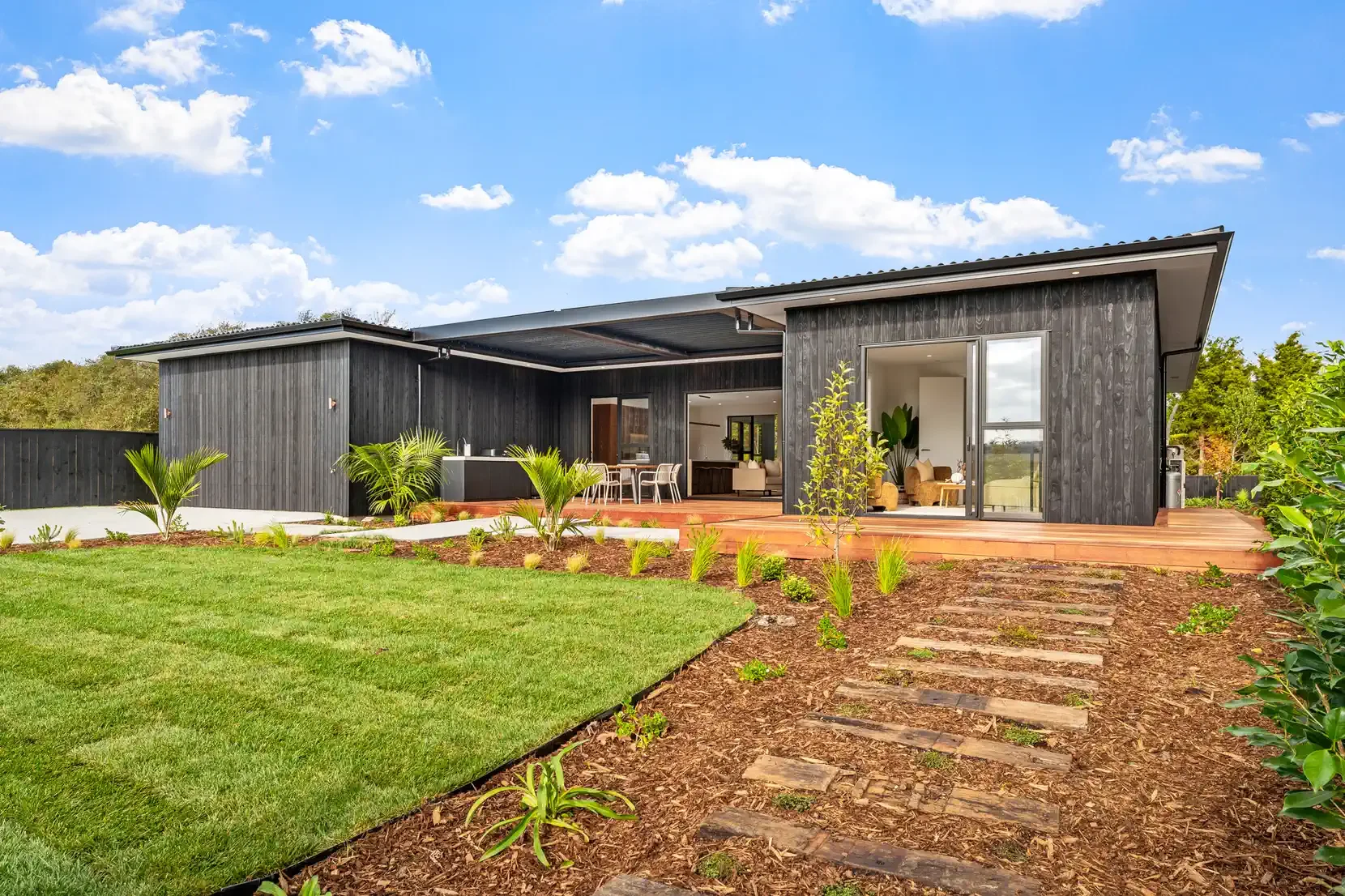 Modern black luxury home with a beautifully landscaped front yard