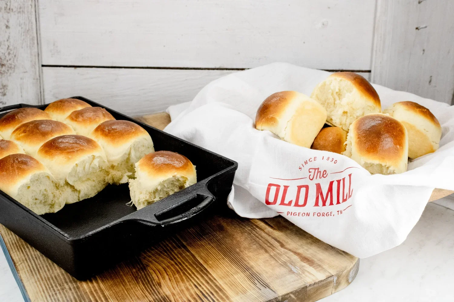 Rolls baked in a cast iron skillet and a basket of rolls with a kitchen towel that says The Old Mill.