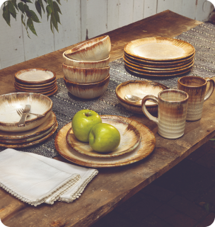 Handcrafted dinnerware featuring Flowering Dogwood Glaze on a rustic wooden table with creme linens