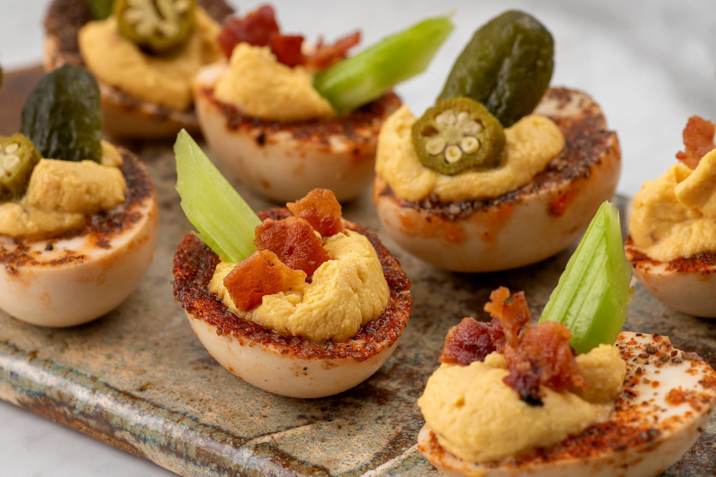 Close-up of bloody mary deviled eggs with cheese and veggie garnishes