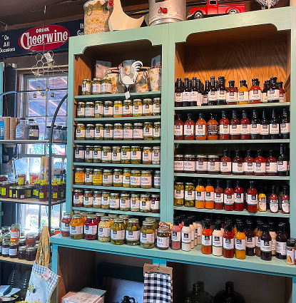 Shelves displaying an assortment pantry goods like, jams, jellies, and spices.