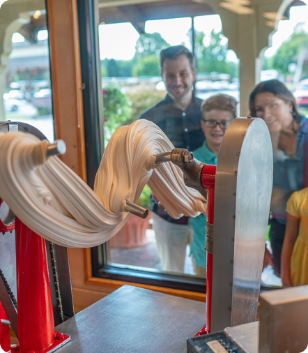 A century-old machine makes salt-water taffy in the storefront window while a family looks in
