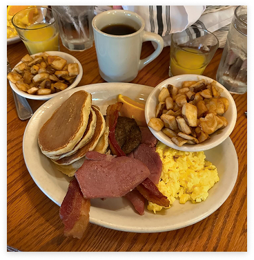 Closeup of a heart traditional Southern breakfast of farm fresh eggs cooked to order, small pancakes, our own stone ground corn grits, homemade biscuits with home fried potatoes
