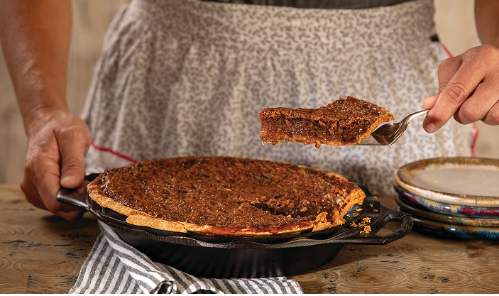 A baker slices a scratch-made, traditional pecan pie