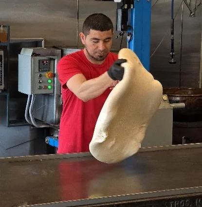 A worker preps candy for the 100-year-old taffy pulling machine