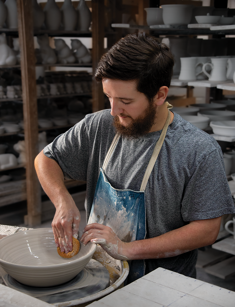 Photo of a potter working on a bowl at the Potter House Cafe