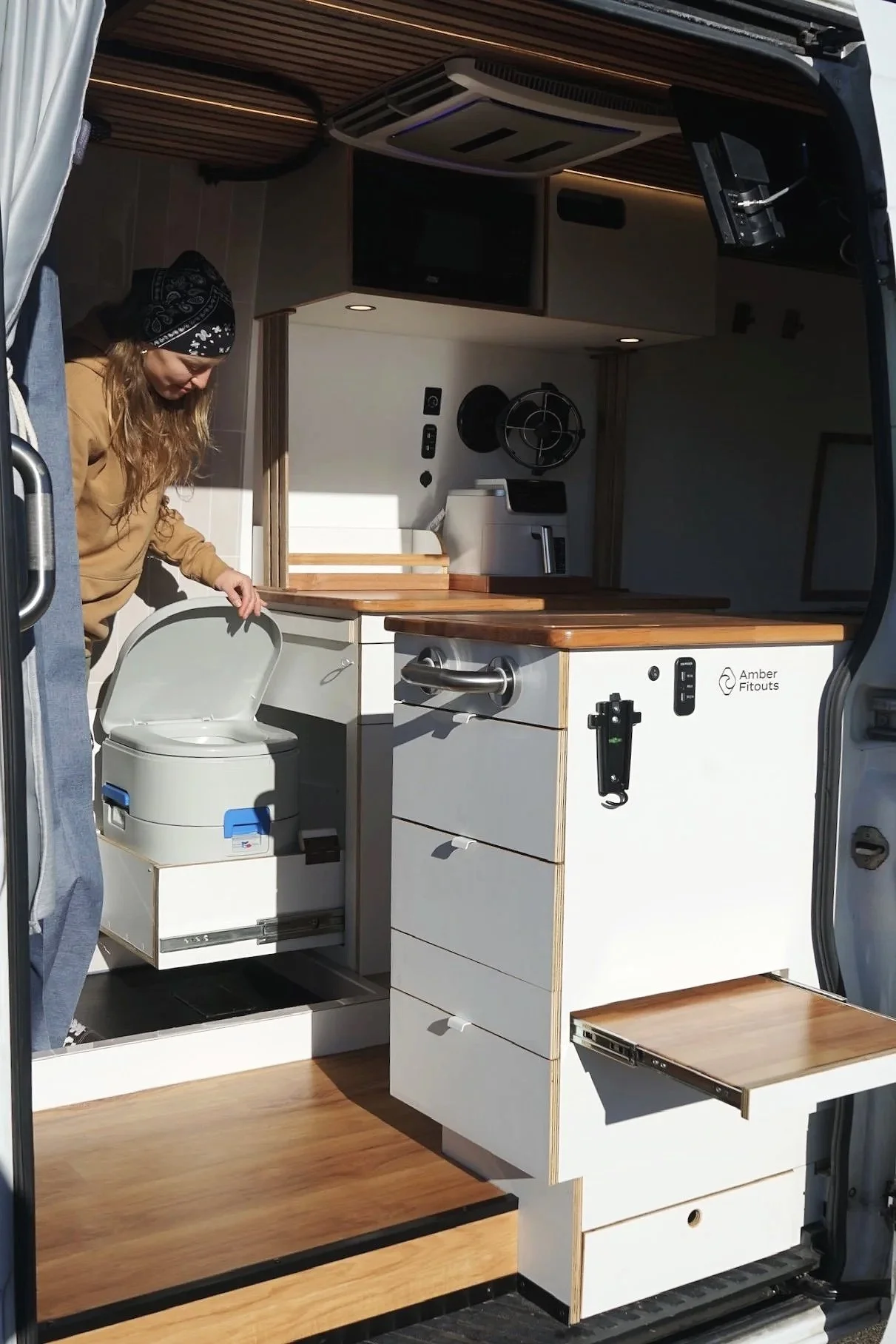 Mercedes Sprinter LWB campervan conversion with pull-out storage drawer, white cabinetry and timber finishes by Amber Fitouts.