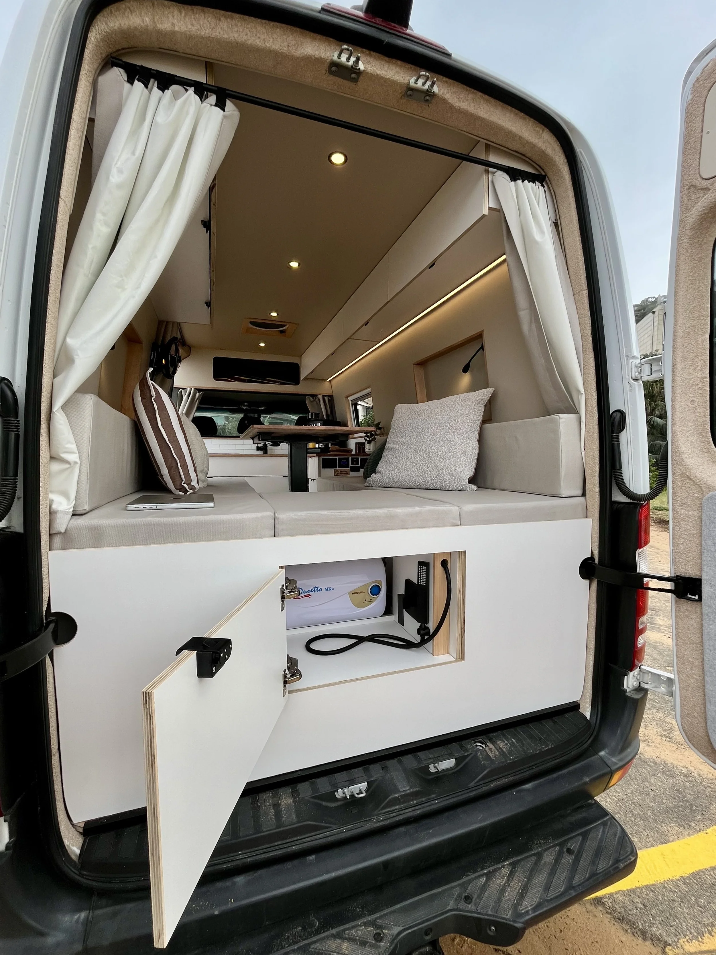 Rear view of Mercedes Sprinter MWB High Roof campervan conversion with bed, curtains and storage
