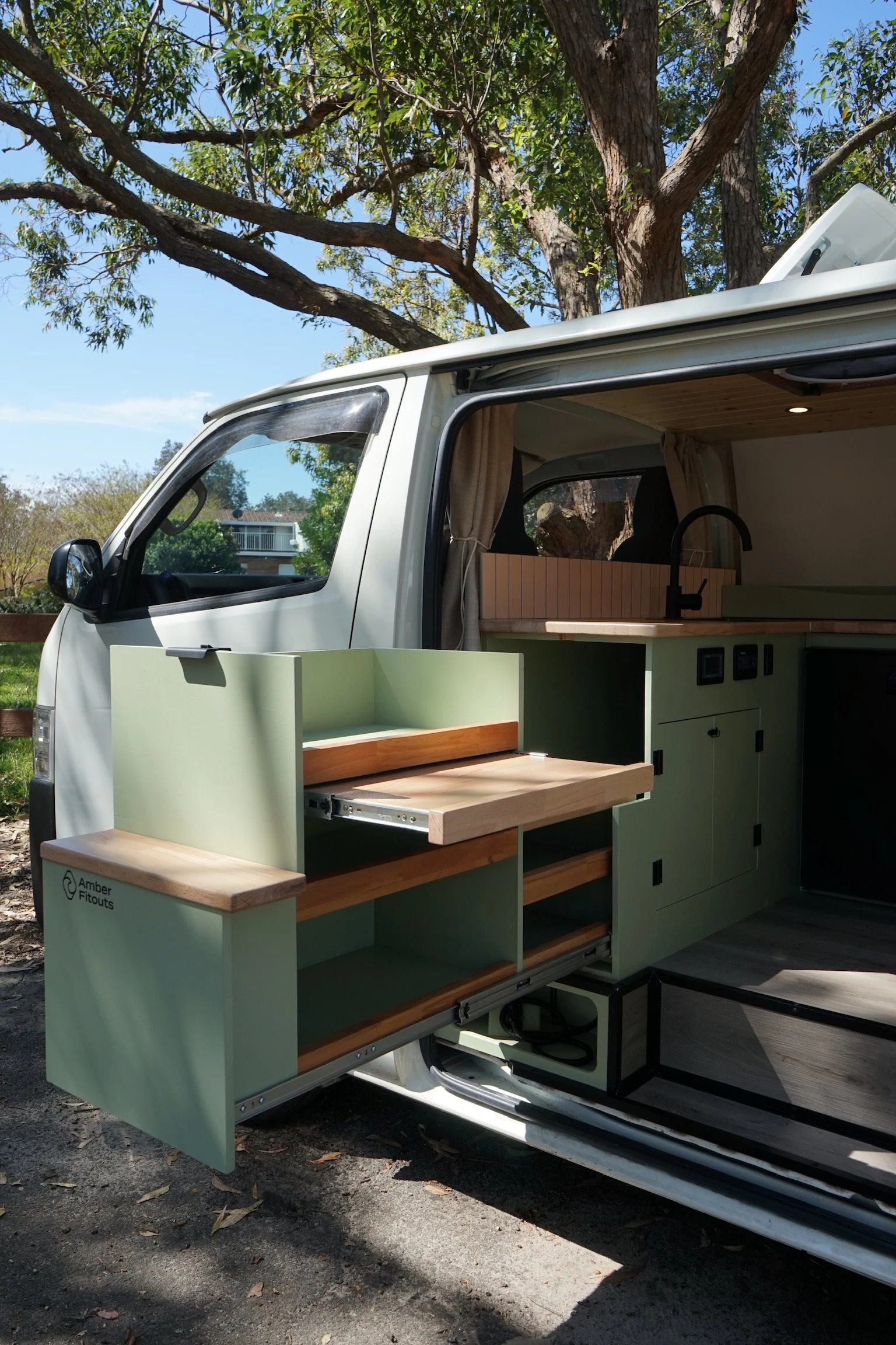 Toyota Hiace LWB campervan conversion with pull-out outdoor kitchen, timber benchtop and green cabinetry.
