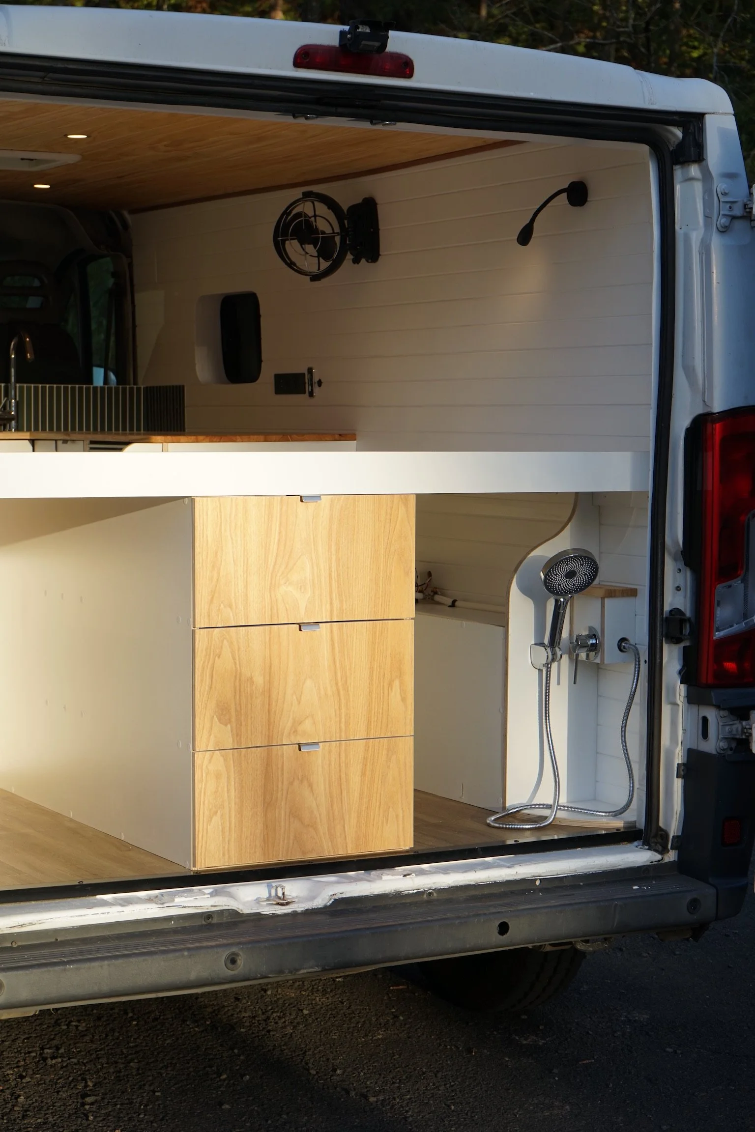 Fiat Ducato campervan conversion with rear shower setup, custom cabinetry, timber ceiling and outdoor shower.