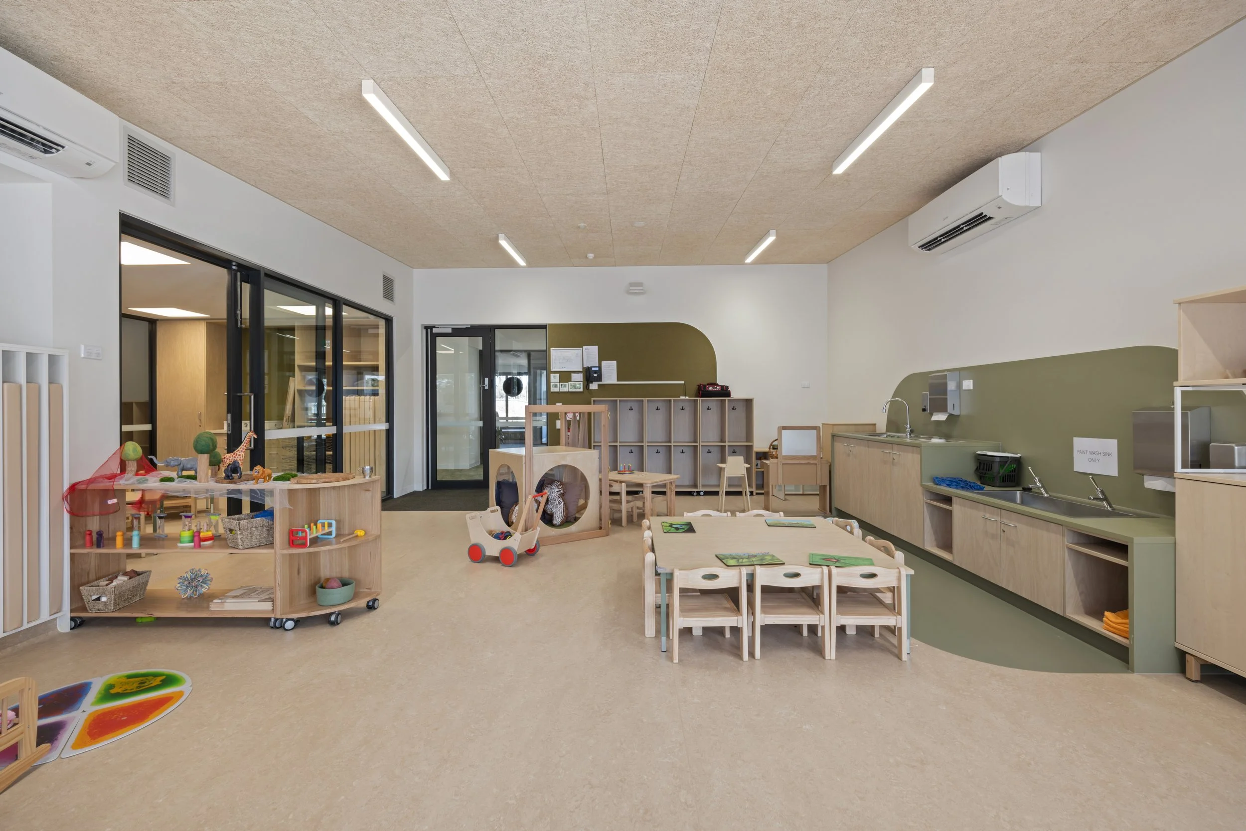 Interior of a children's playroom with small furniture, toys, and a pretend kitchen area.
