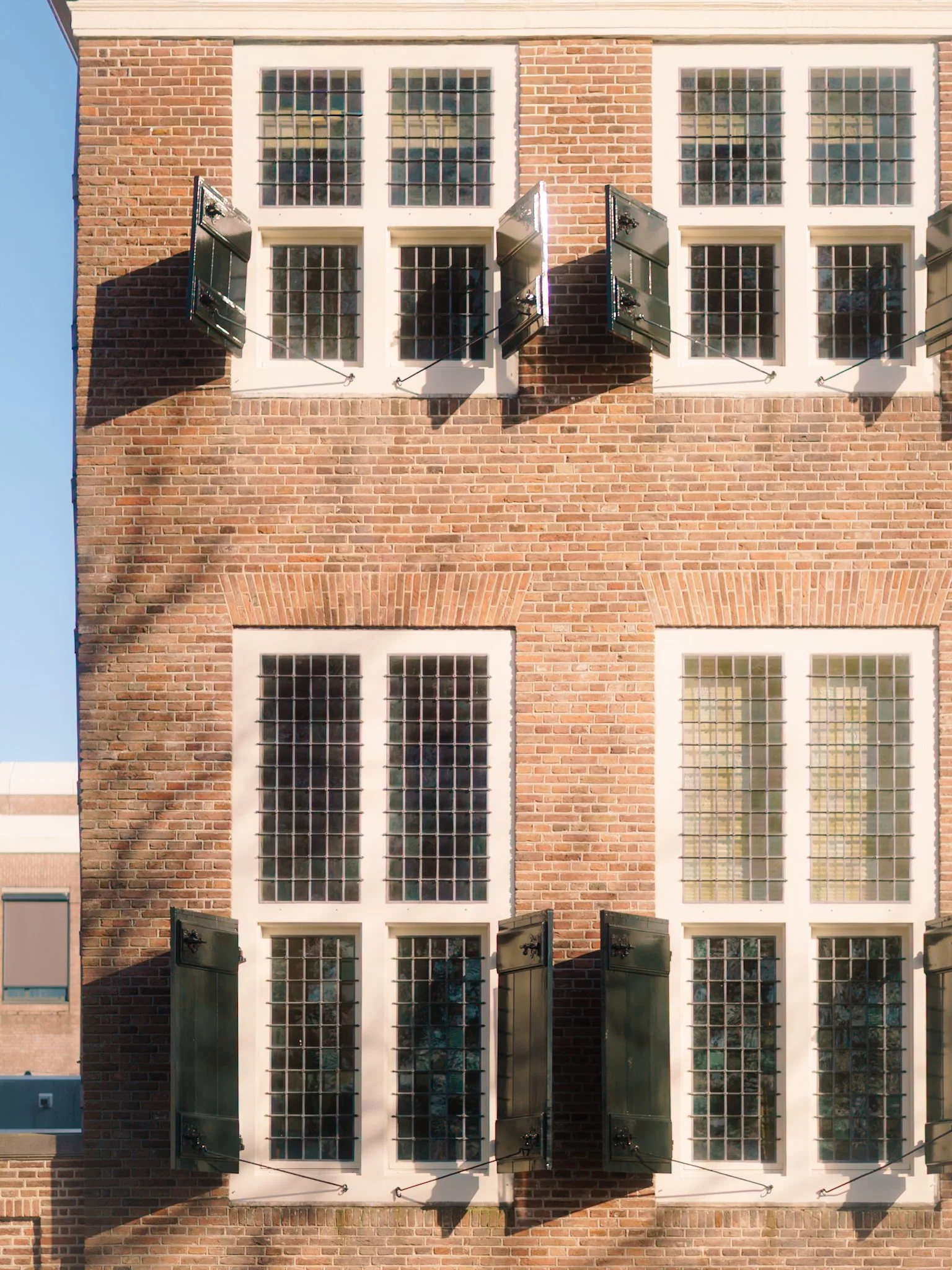 Bovenaanzicht van een rood bakstenen gebouw met grote ramen en open luiken.