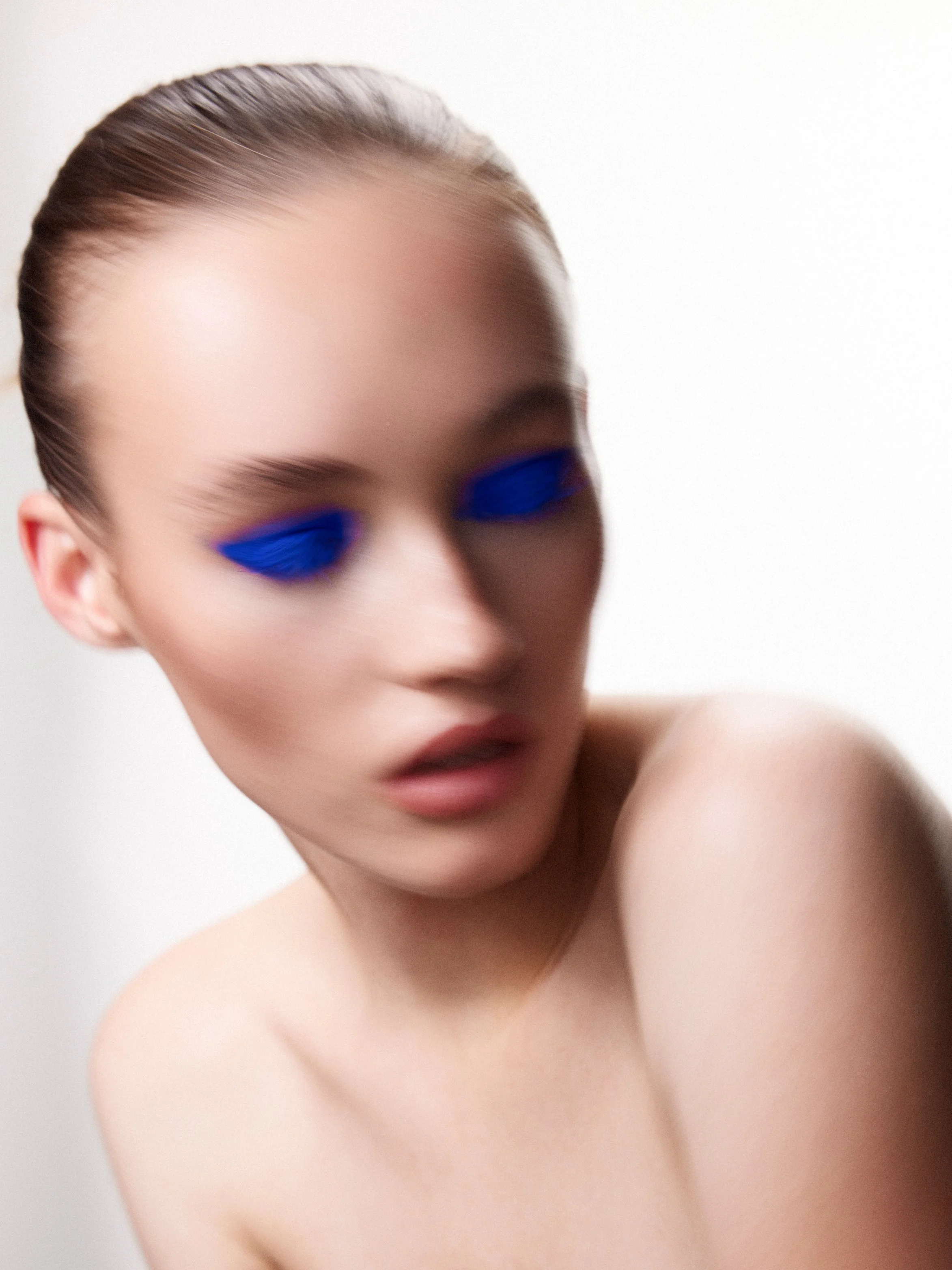 An abstract blurred beauty portrait of a female model wearing a smokey blue eye