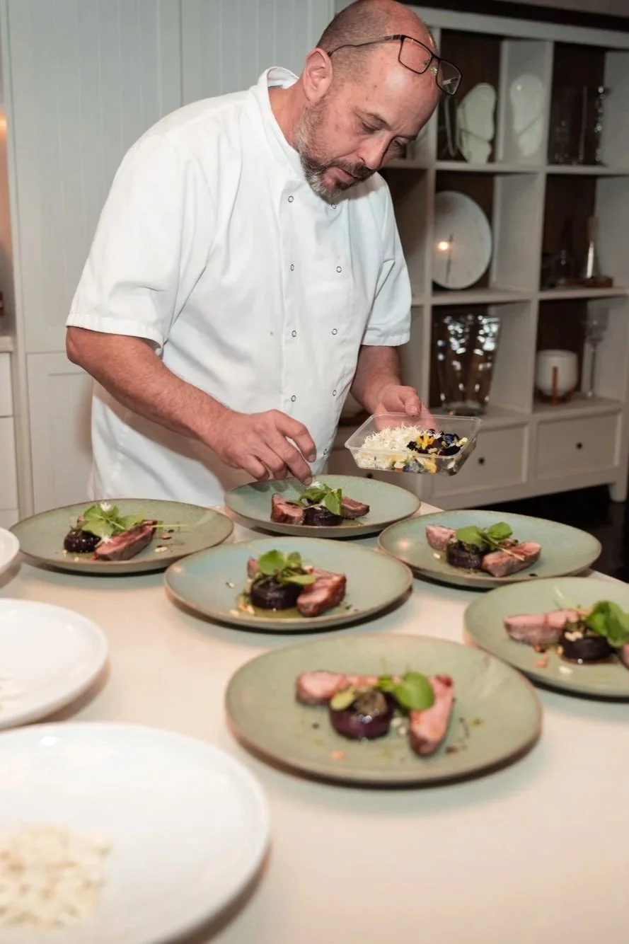 Chef garnishing plates with food in a restaurant kitchen.