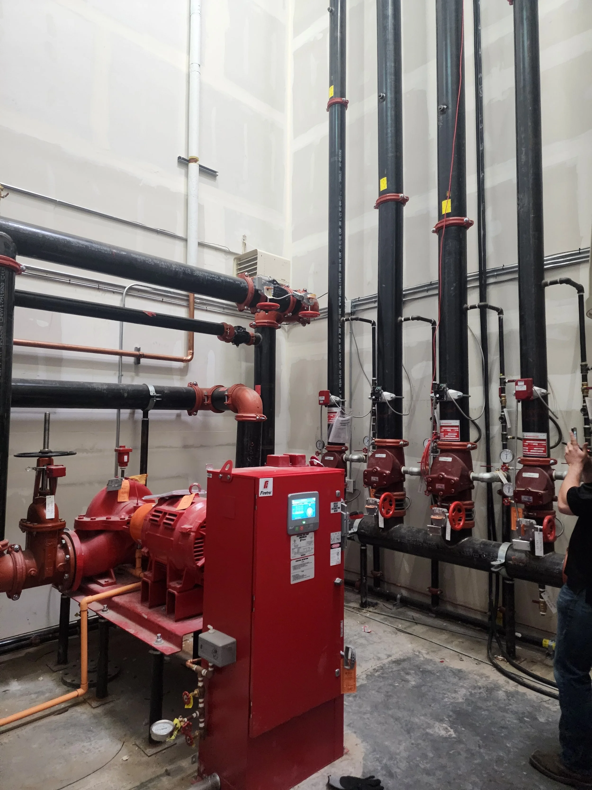 Fire protection system with red fire pump and black pipes in an industrial room.