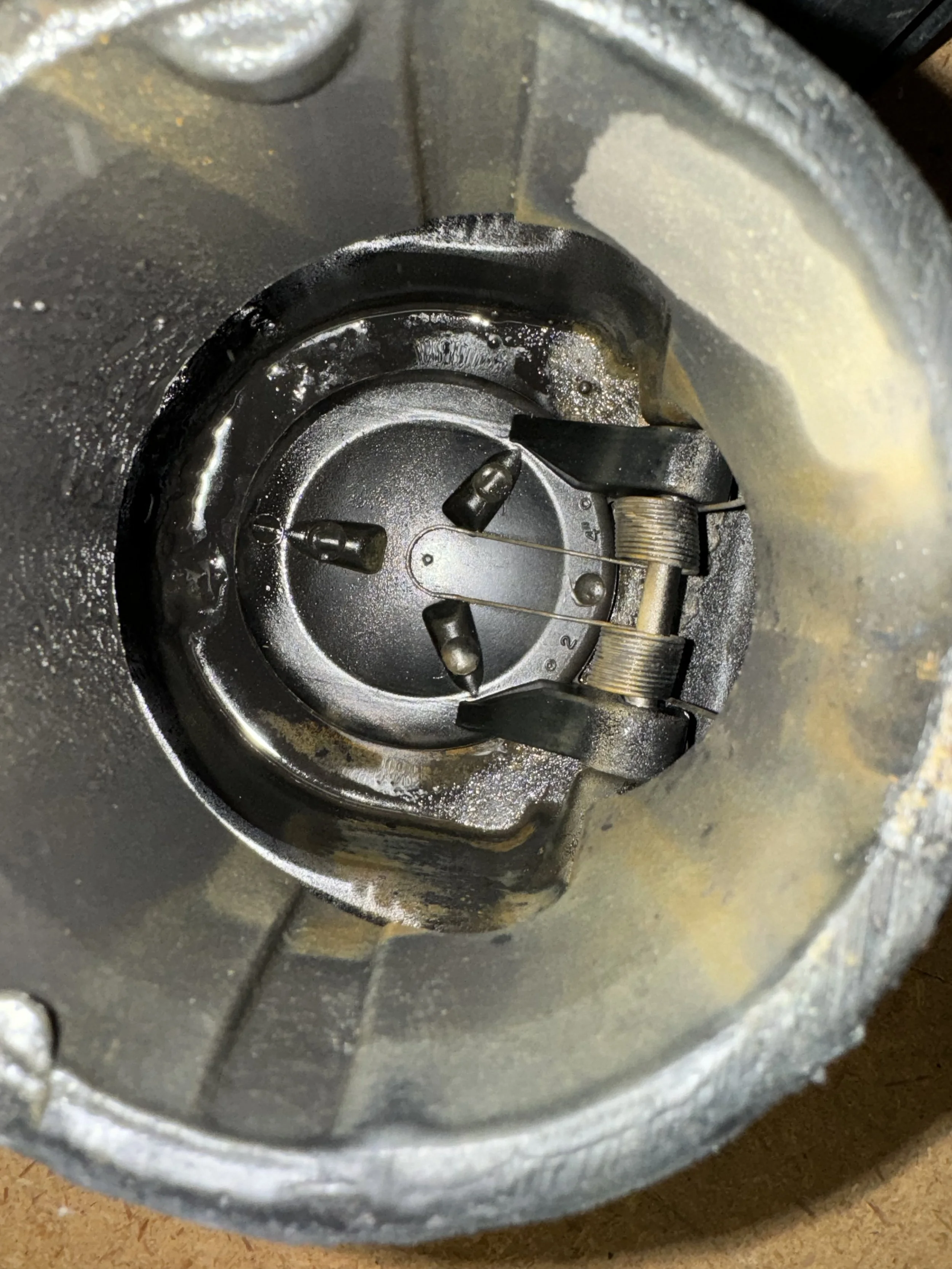 Close-up of a metal mechanical component with springs and pins inside a cylindrical container.