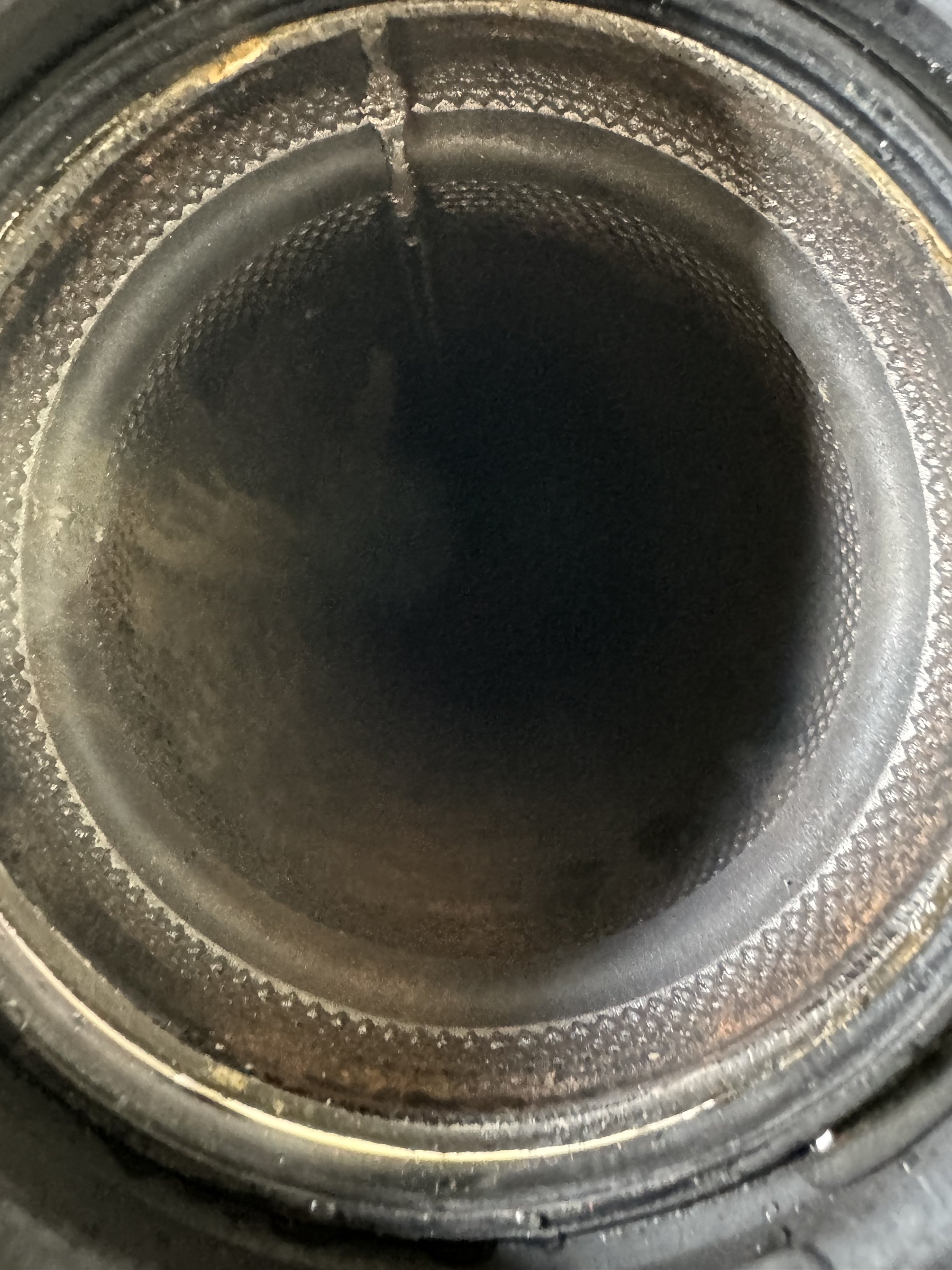 Close-up view of the inside of a black, empty metal pipe or tube with a corroded and textured surface.