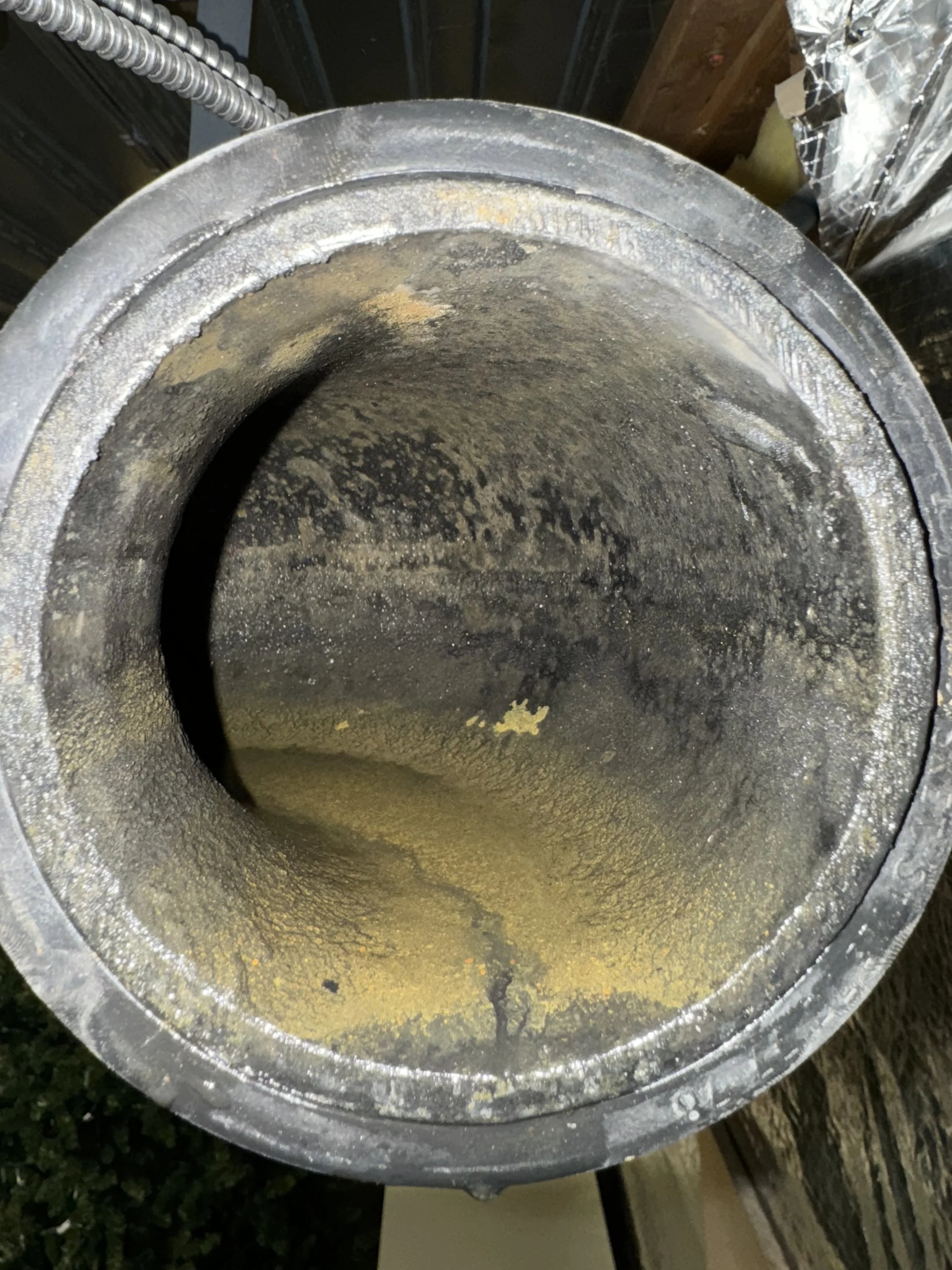 Interior of a large metal pipe with rust and residue inside.
