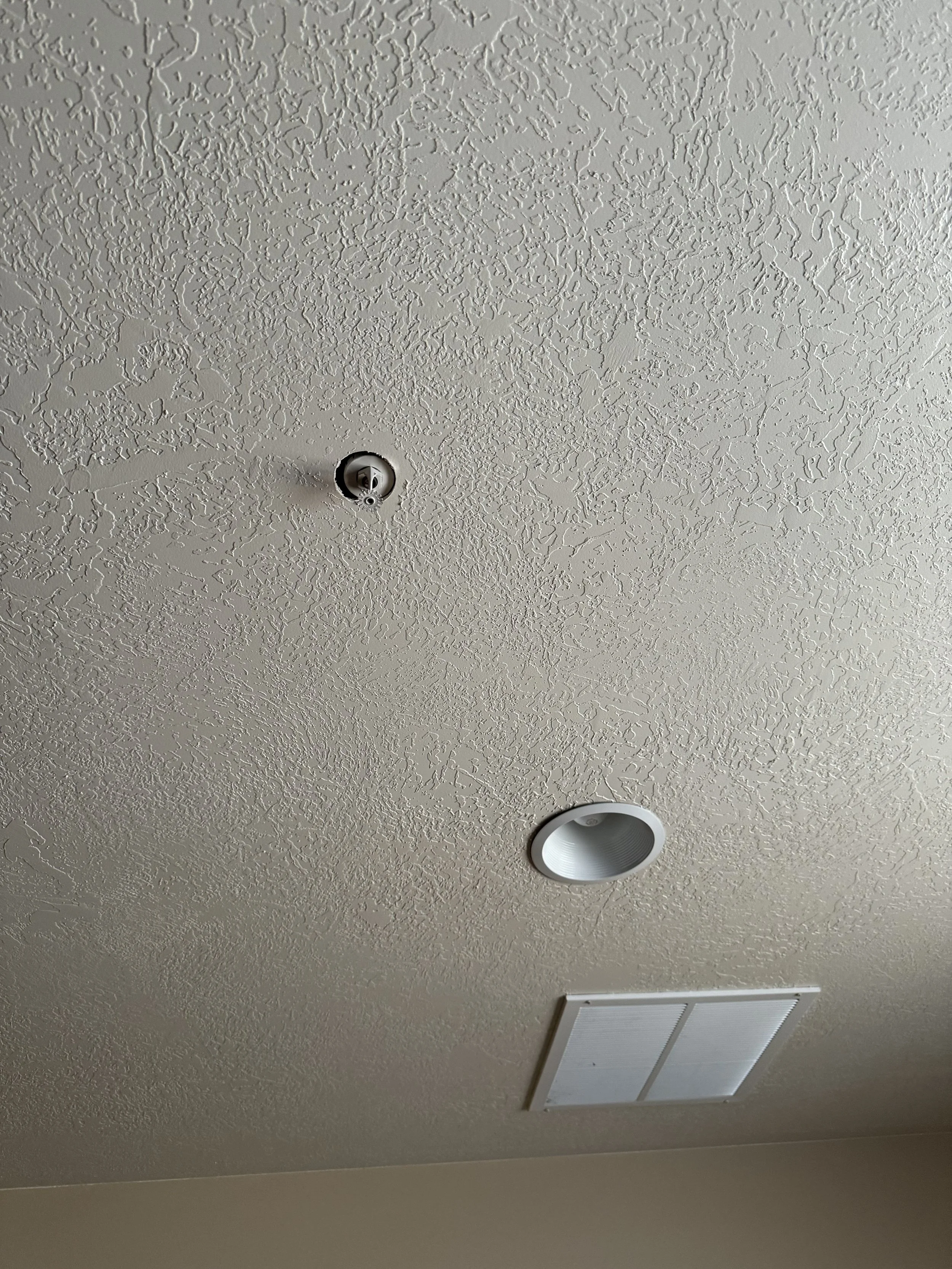 Ceiling with a smoke detector, a recessed light fixture, and an air vent.