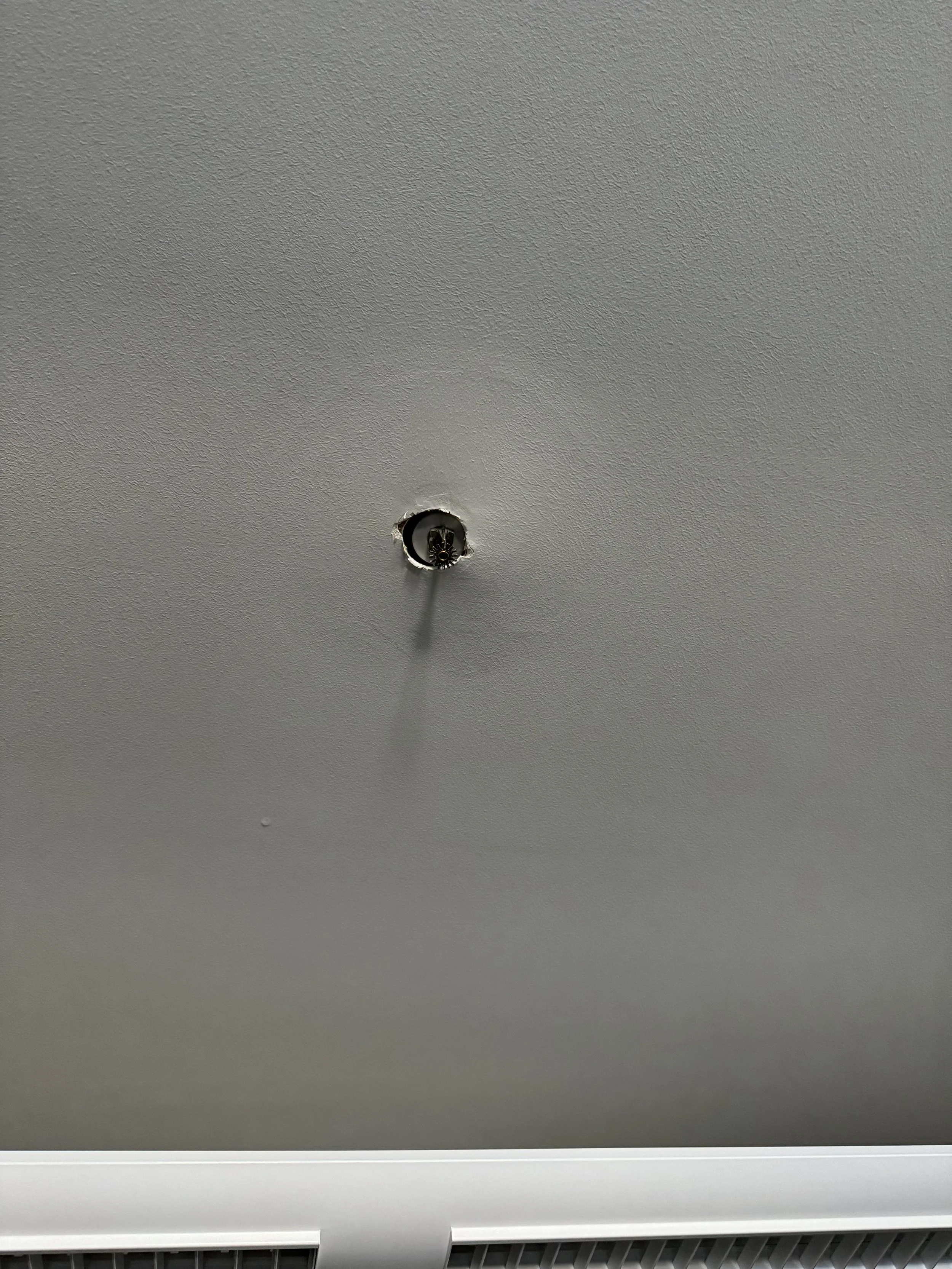 Ceiling with an empty light fixture socket and a white air vent at the bottom.