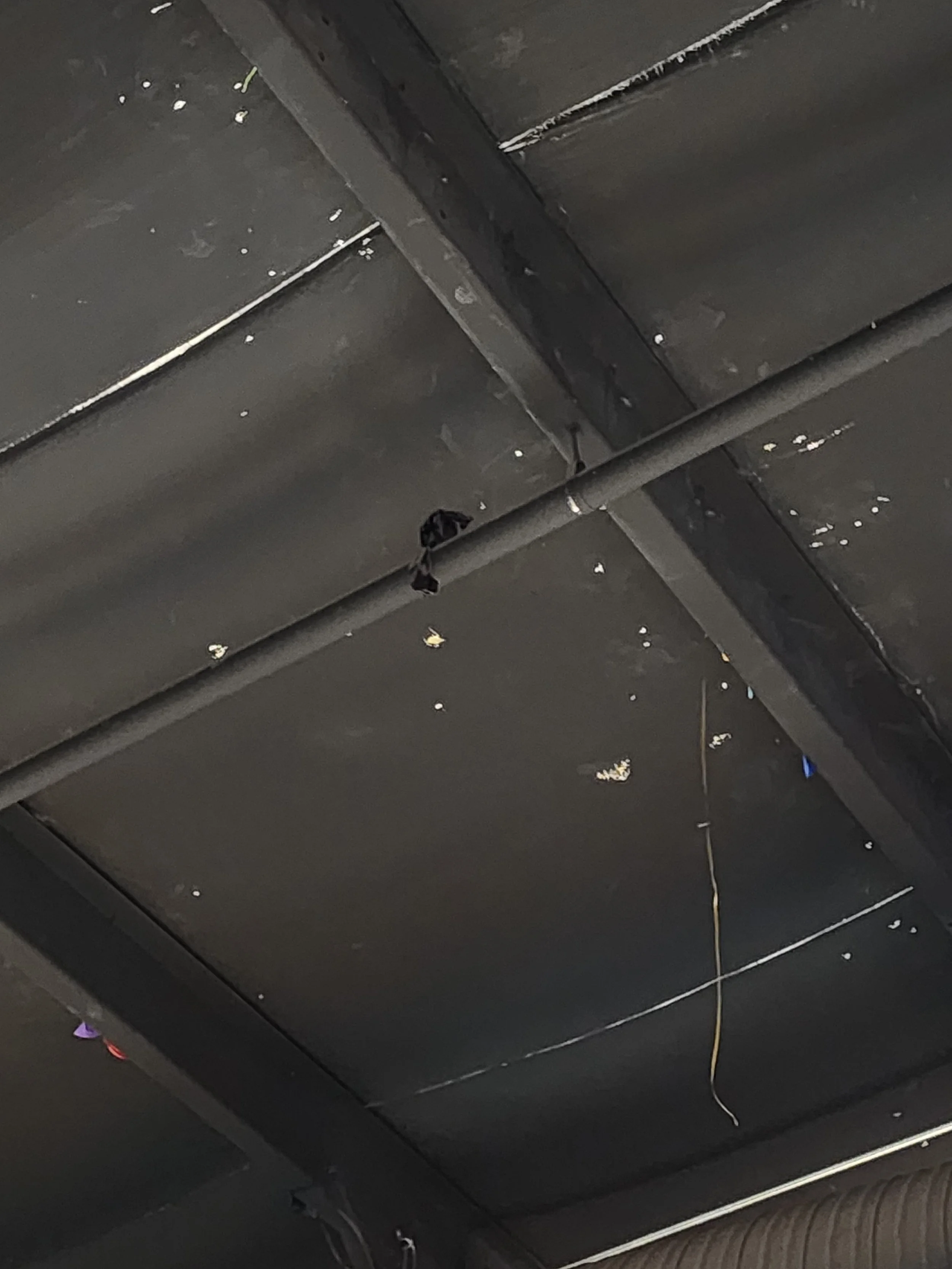 Ceiling with chipped paint, a black wire hanging, and a metal pipe.