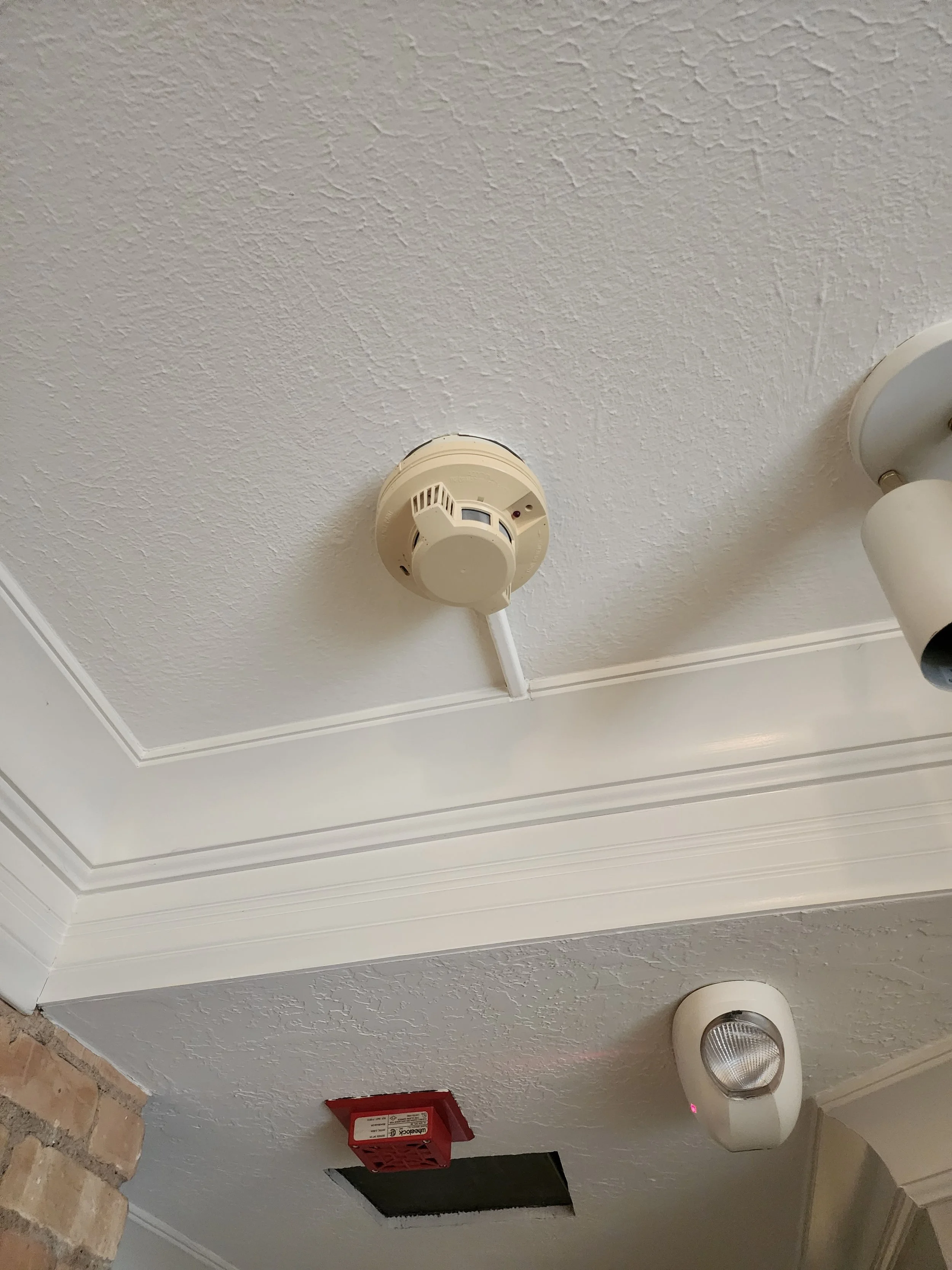 Ceiling with smoke detector, light fixture, fire alarm, and ceiling access panel.