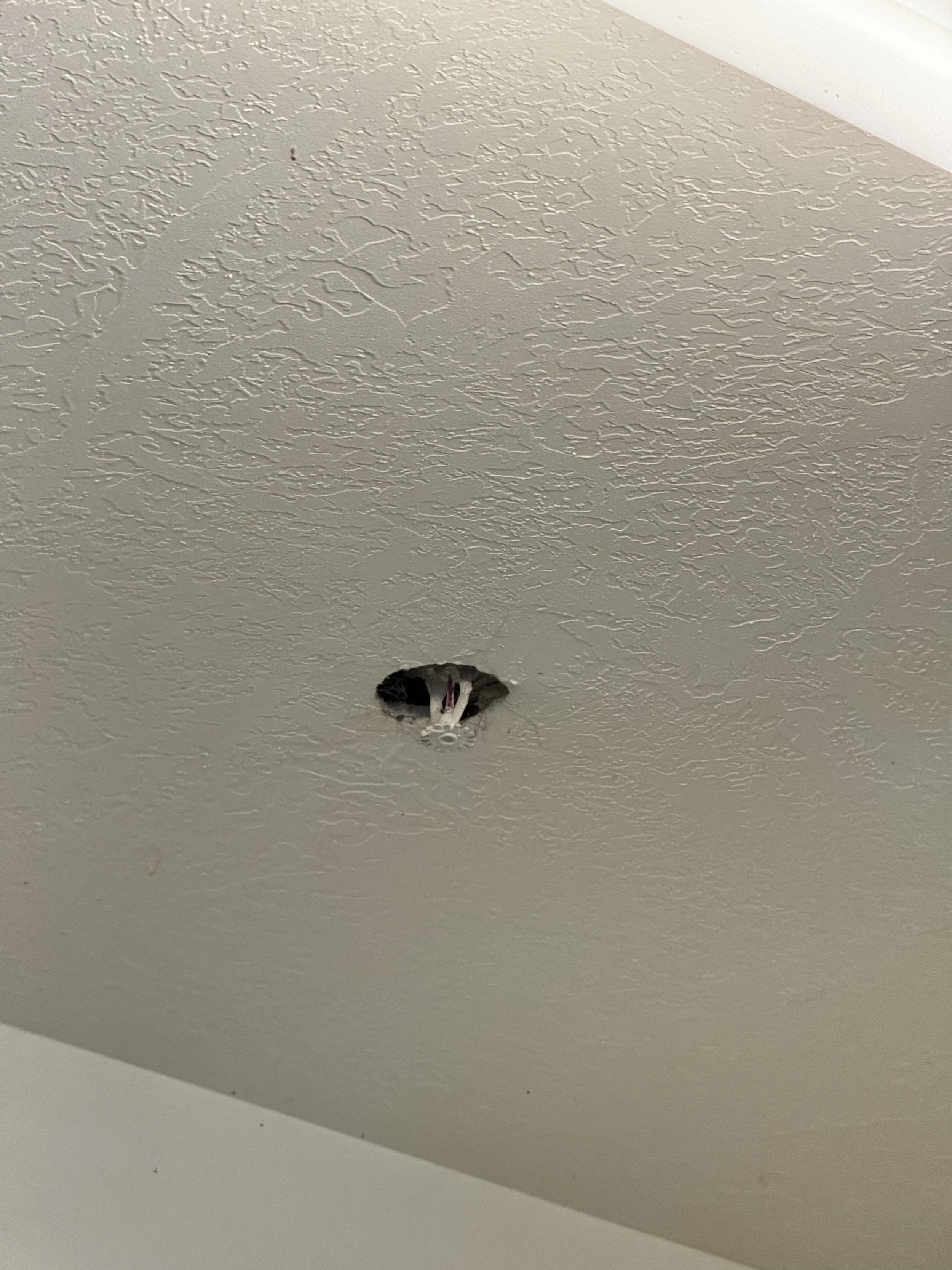 Ceiling with a hole and exposed wires.