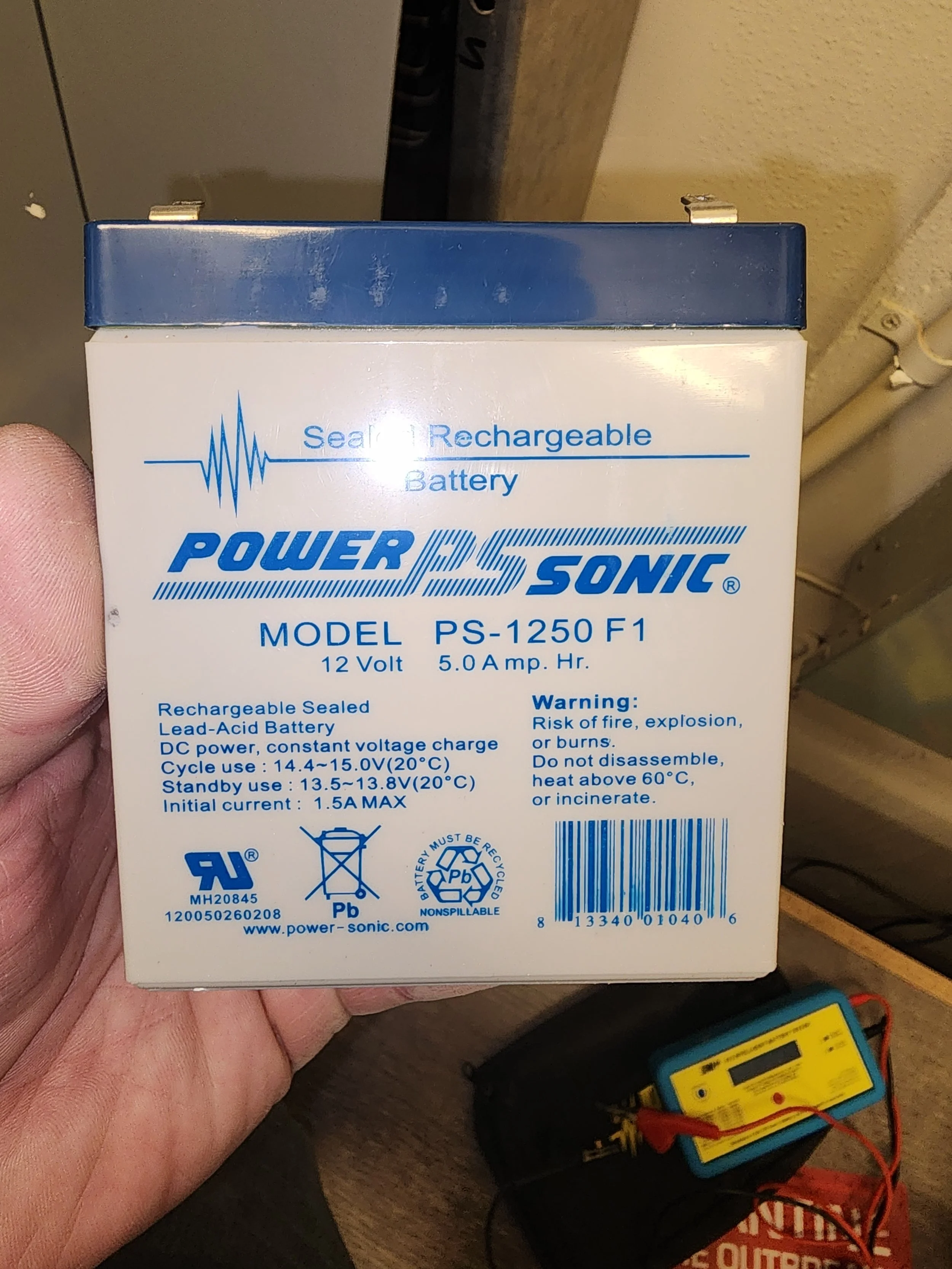 A sealed, rechargeable 12-volt lead-acid battery labeled POWERSONIC MODEL PS-1250 F1, with specifications and safety warnings on the front.