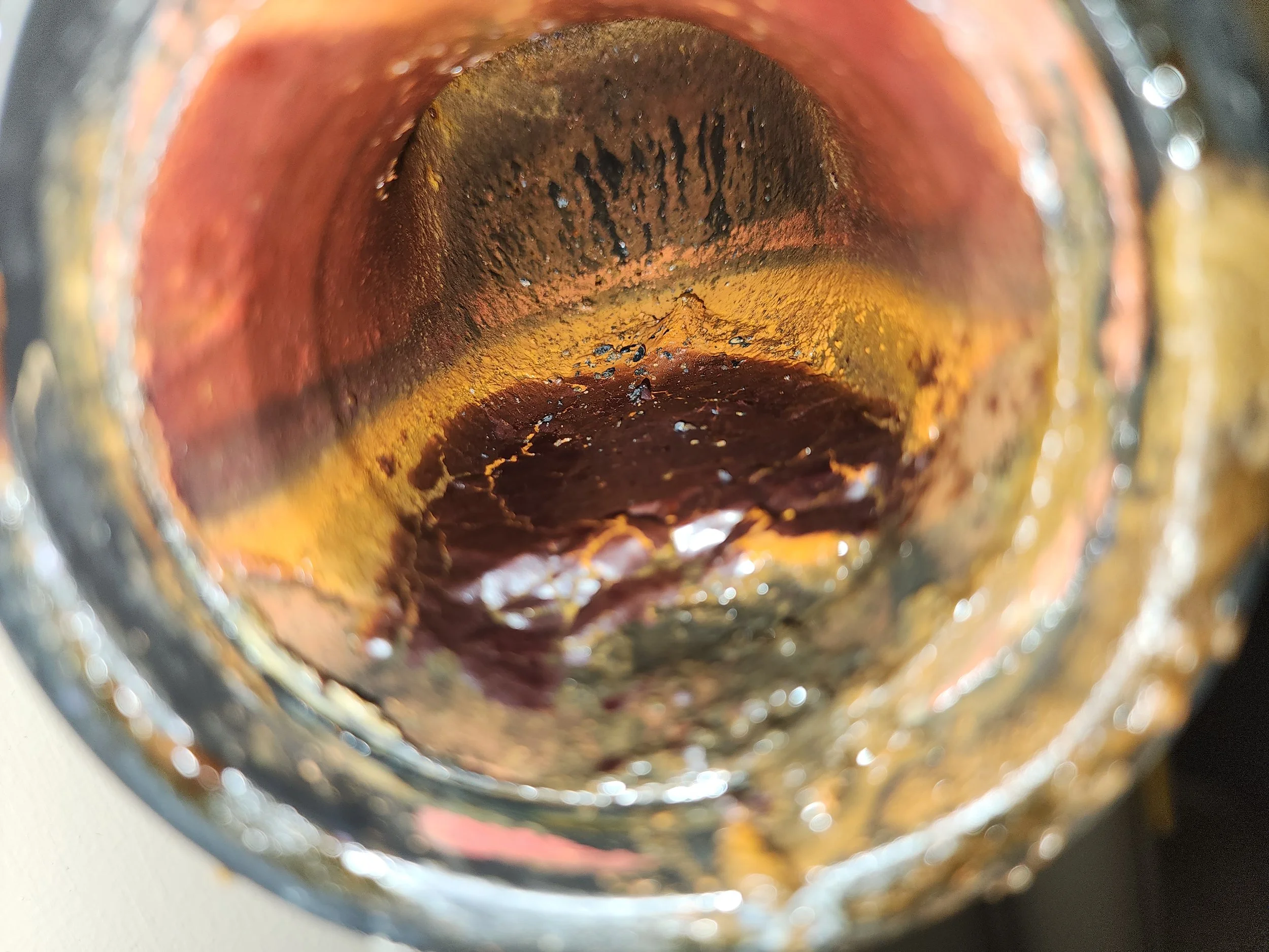 Close-up of the inside of a rusty, corroded pipe with water and rust residue.