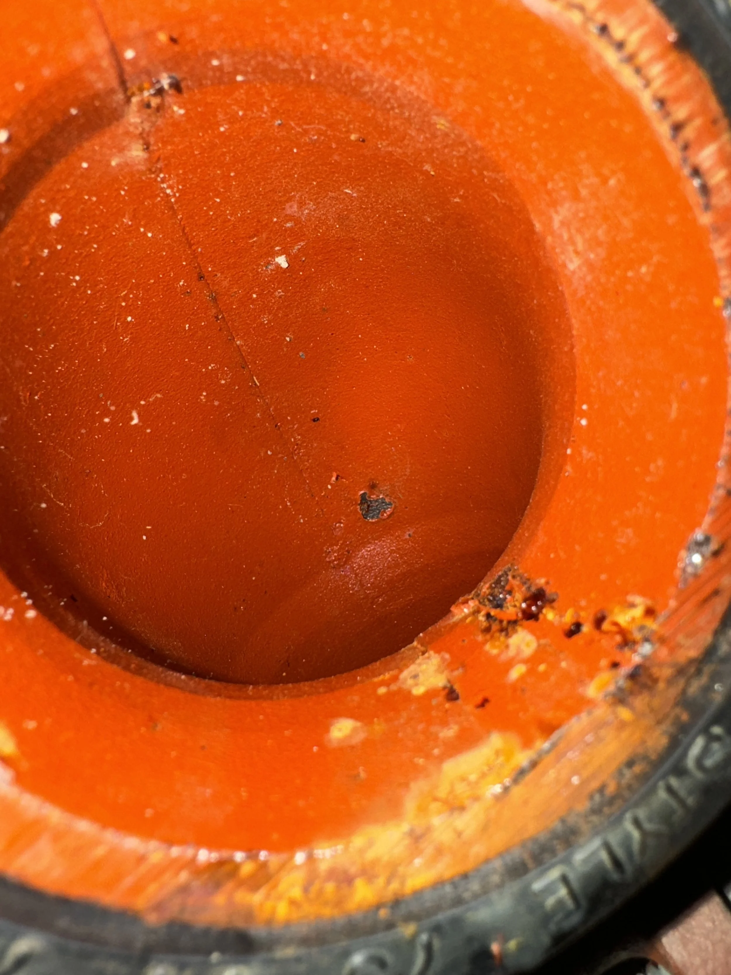 Close-up of an empty orange paint can with some dried paint drips inside.