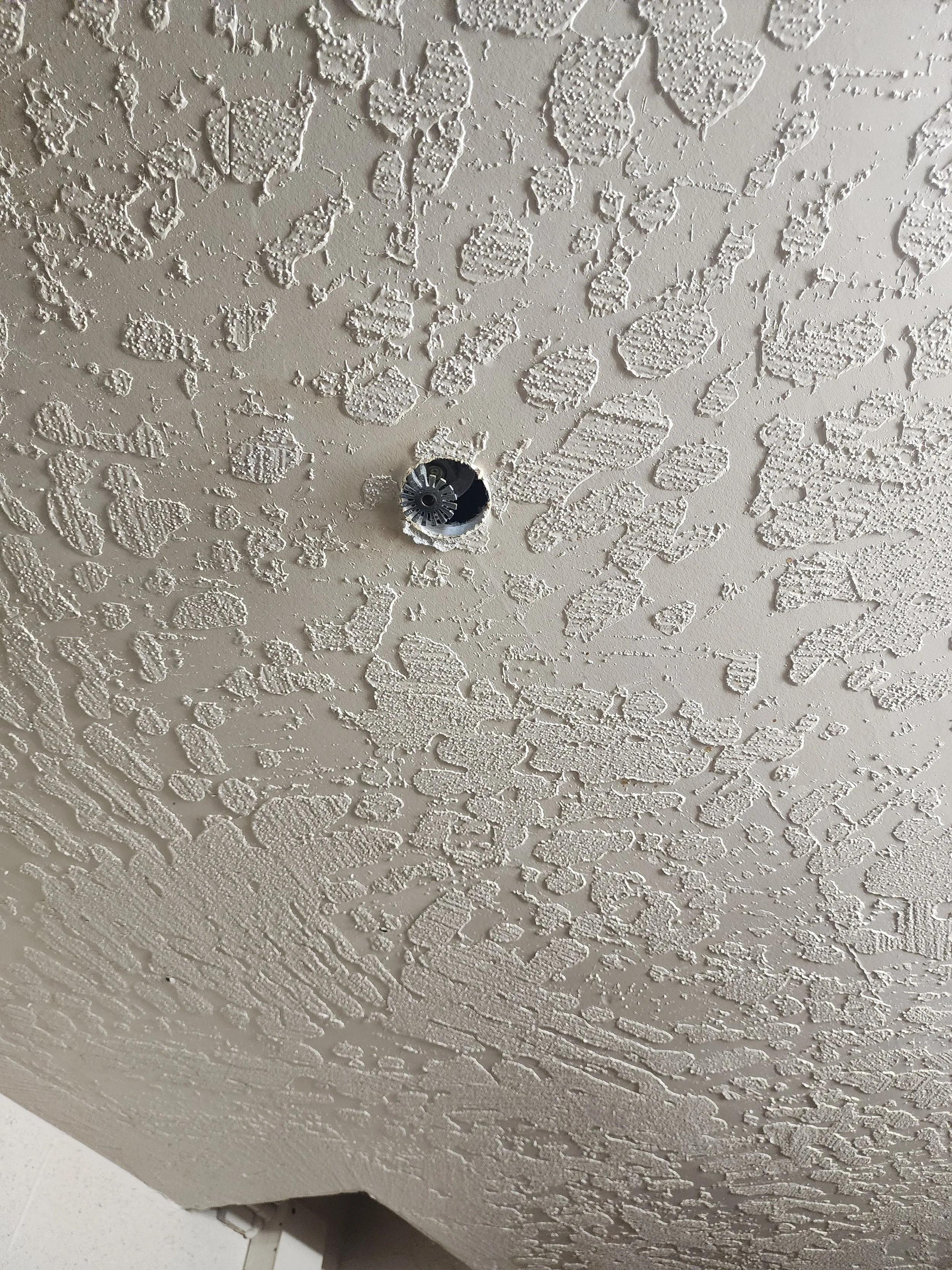 Ceiling with textured finish and an empty electrical or light fixture socket.
