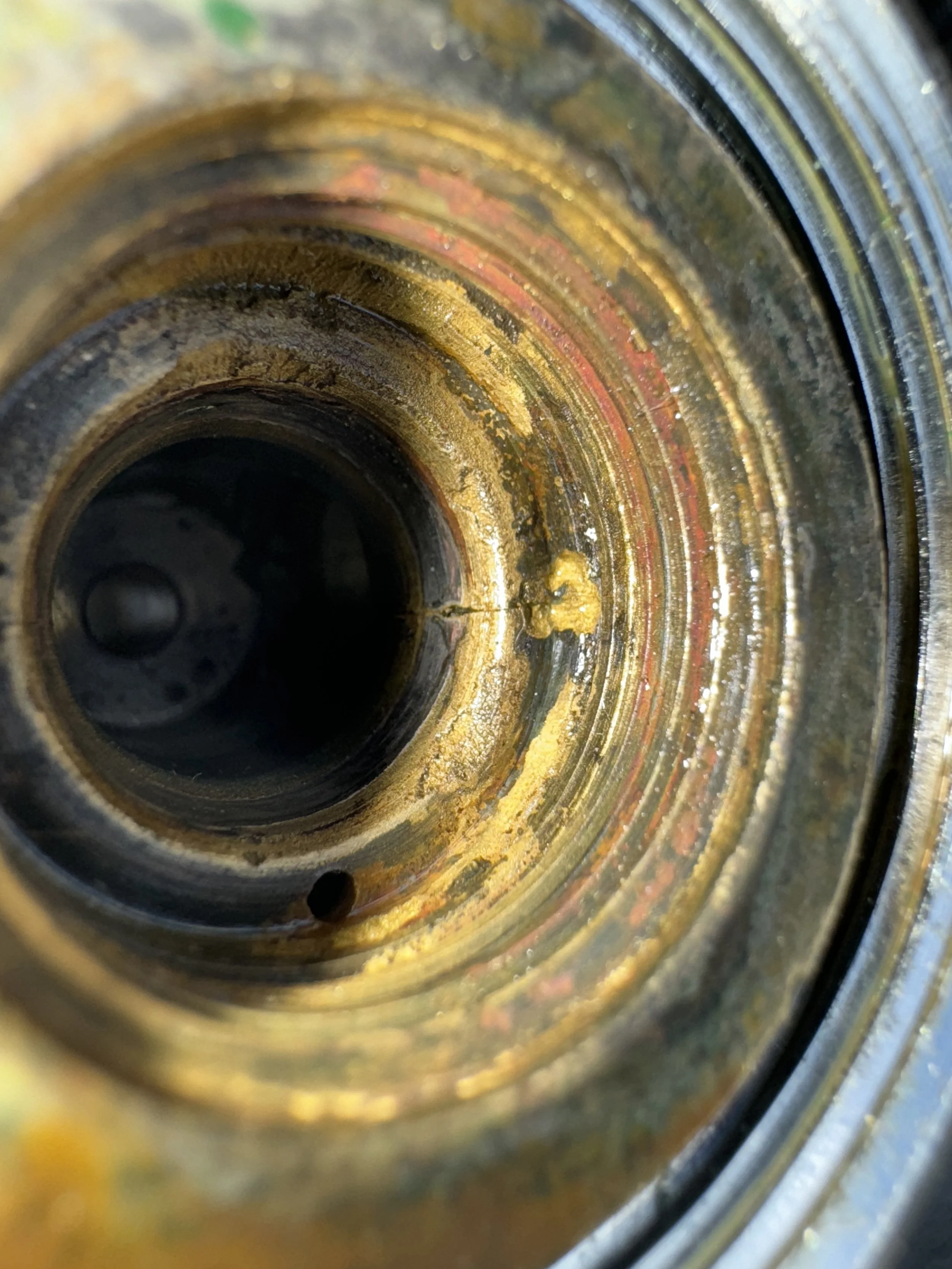 Close-up of a rusty, greasy metal pipe or cylinder tube.