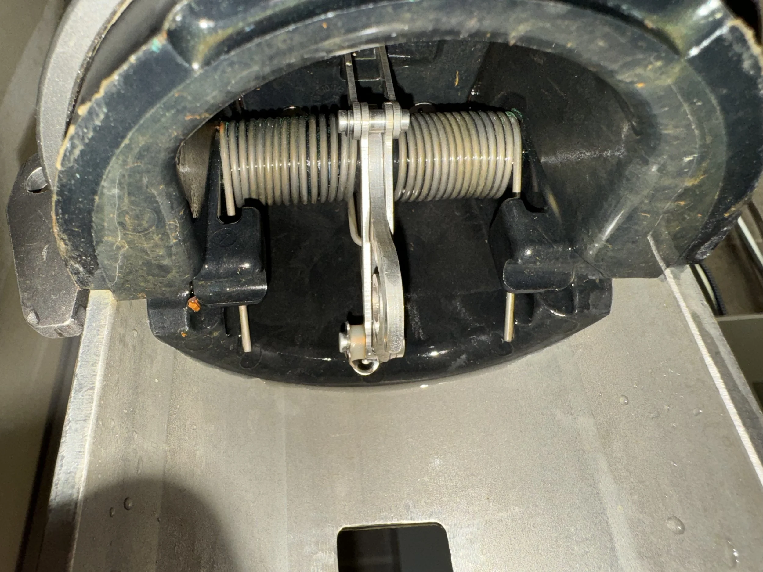 Close-up of the inside of a vintage typewriter showing the typebar mechanism with a coiled spring and metal parts.