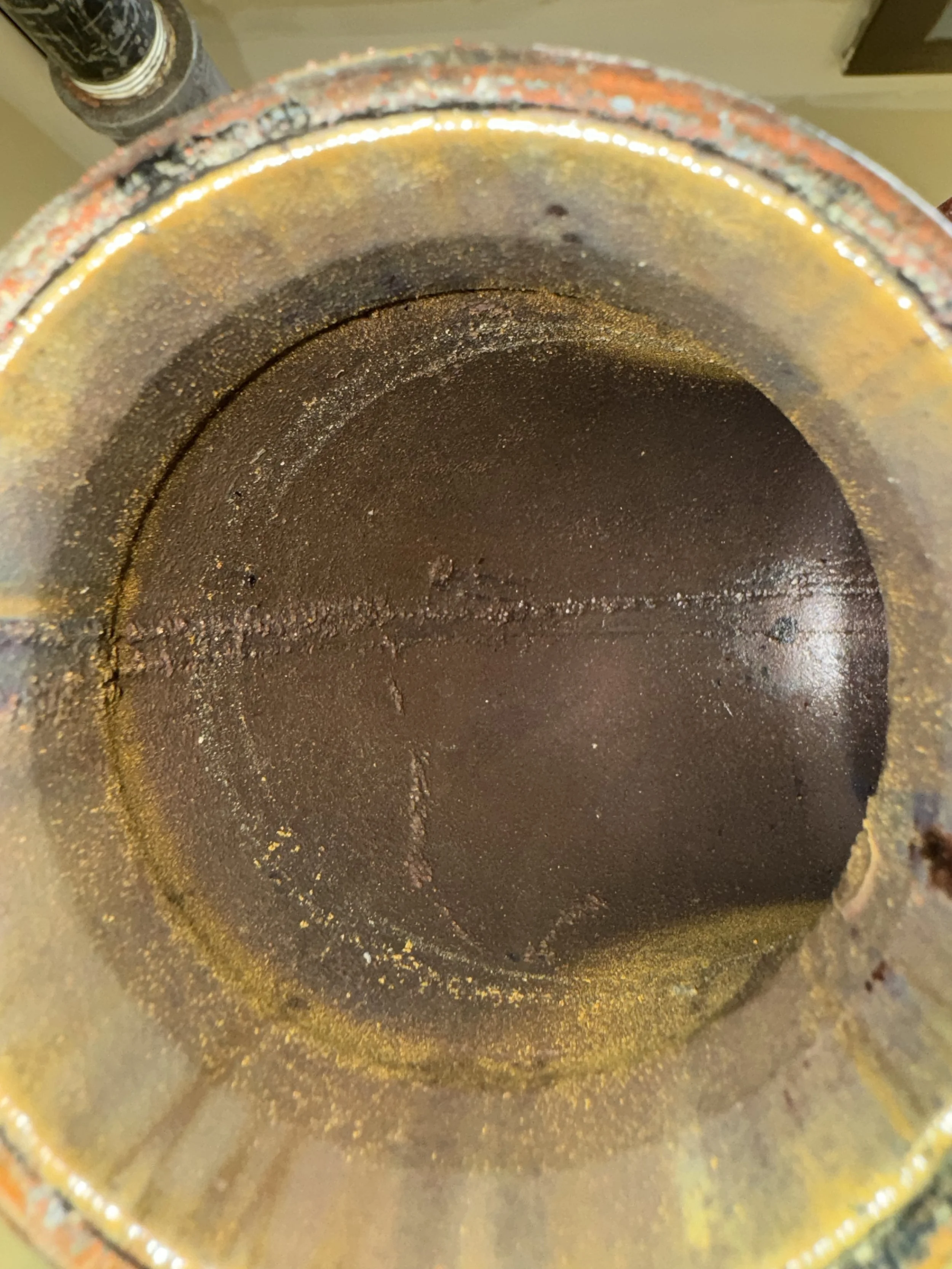Close-up view of the inside of a rusty, greasy metal pipe or cylinder with visible residue and corrosion.