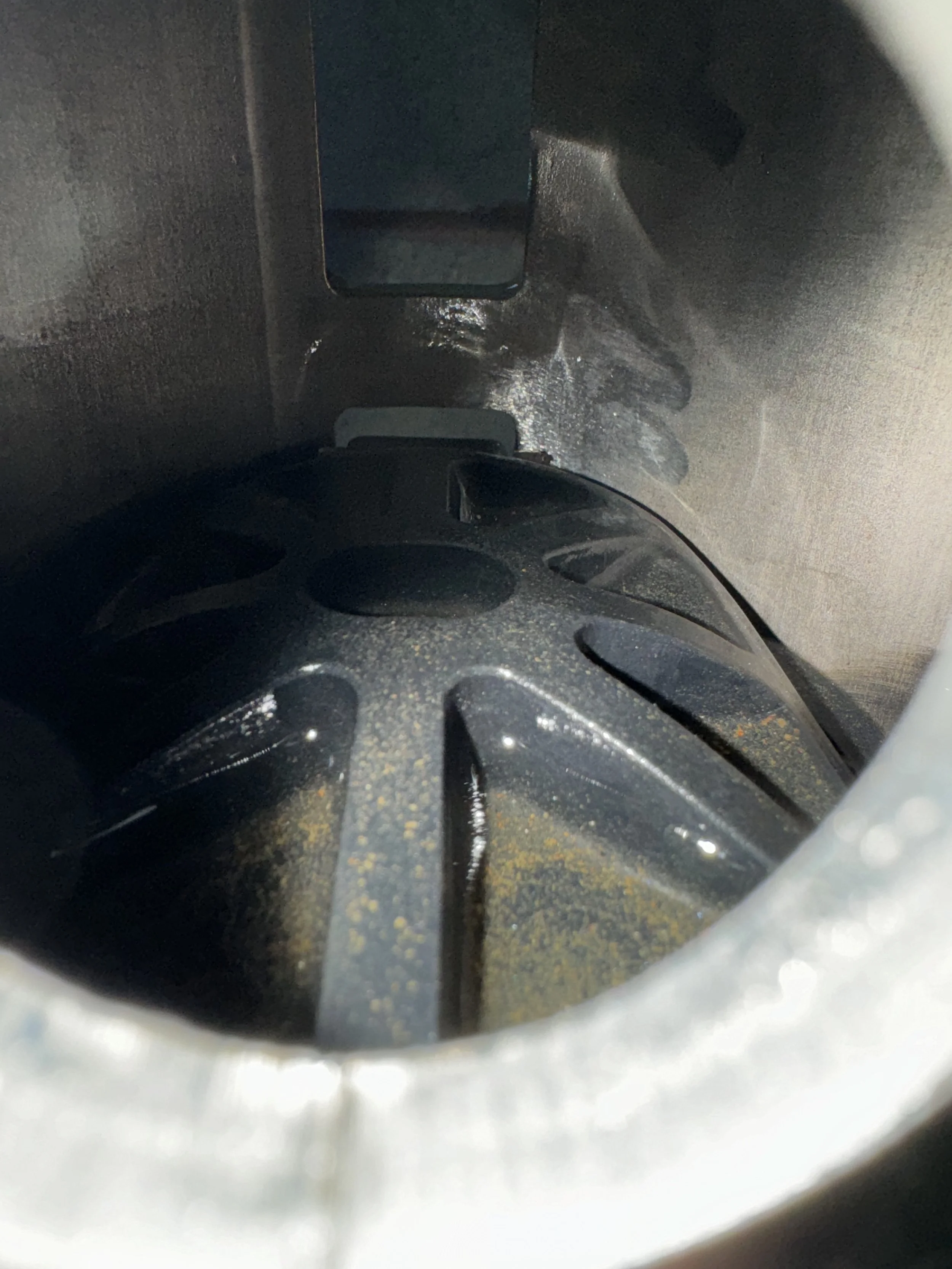 Close-up of a black bicycle helmet inside a locker or storage space, with the helmet resting on a perforated surface.