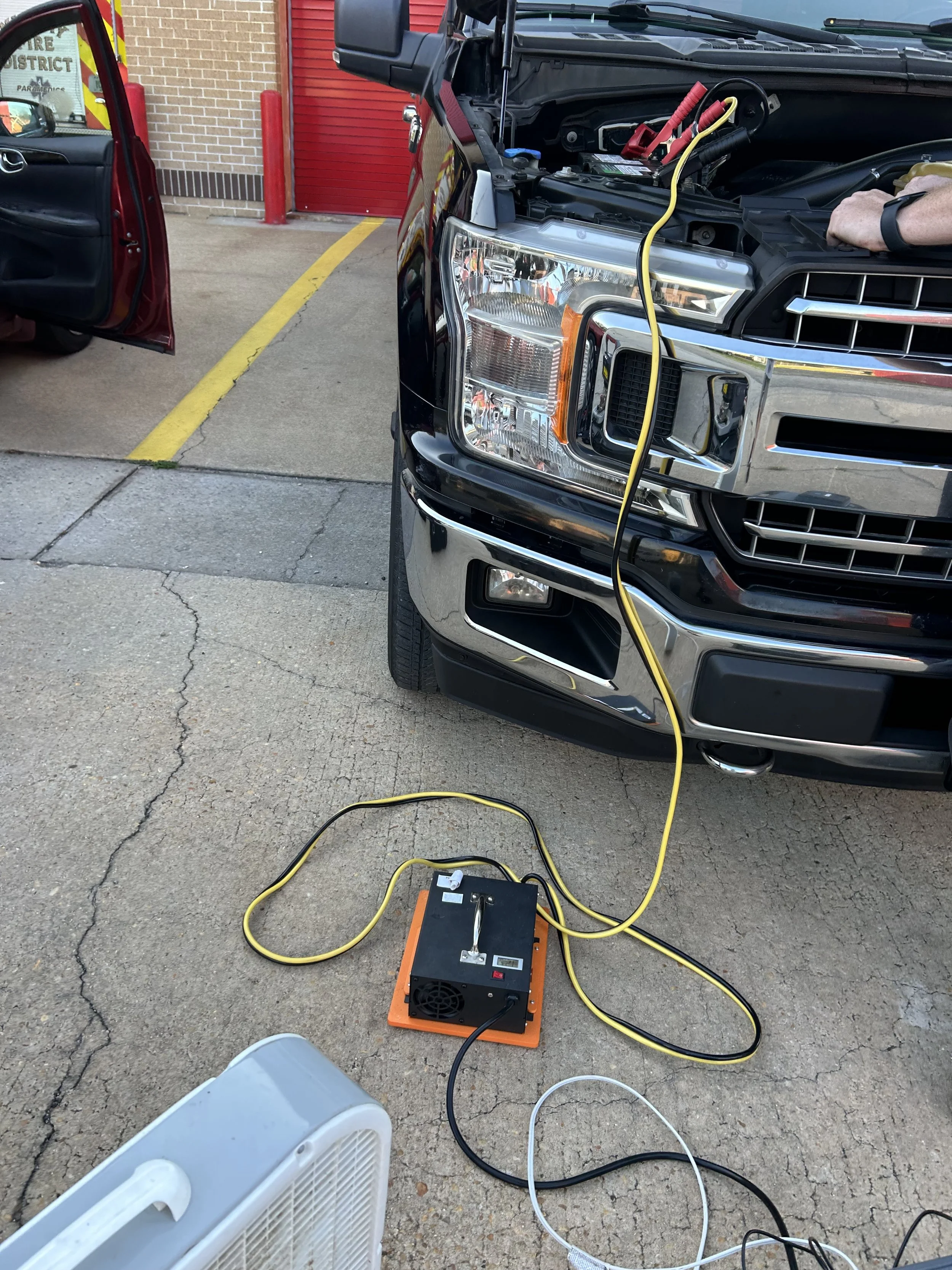2018 Ford F-150 connected to a battery maintainer during flip key programming in Gulf Breeze, Florida.