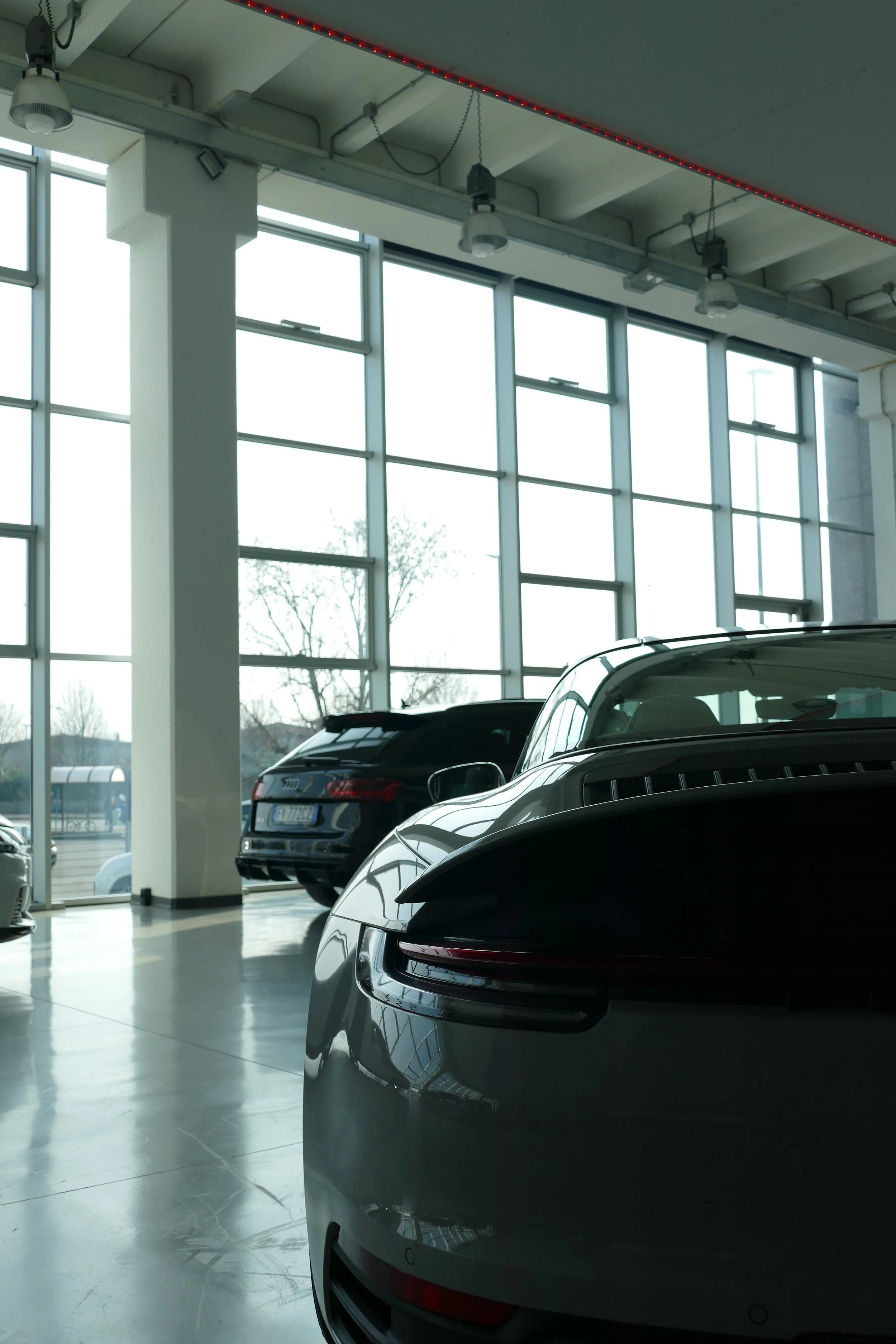 Interno di un concessionario di automobili con Tesla e Audi, grandi finestre che lasciano entrare molta luce naturale.