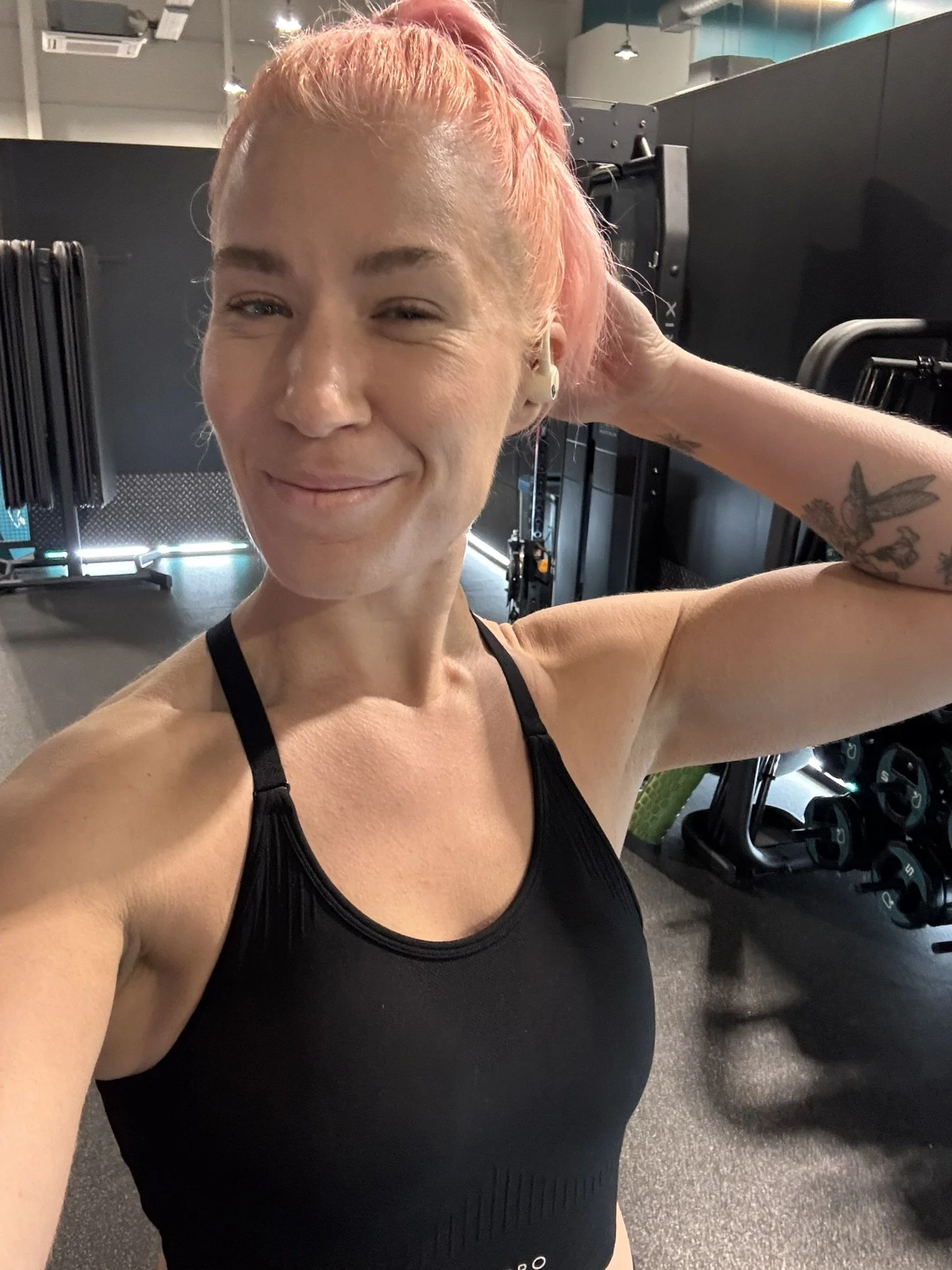 A woman with pink hair smiles. She is a personal trainer in a gym in folkestone