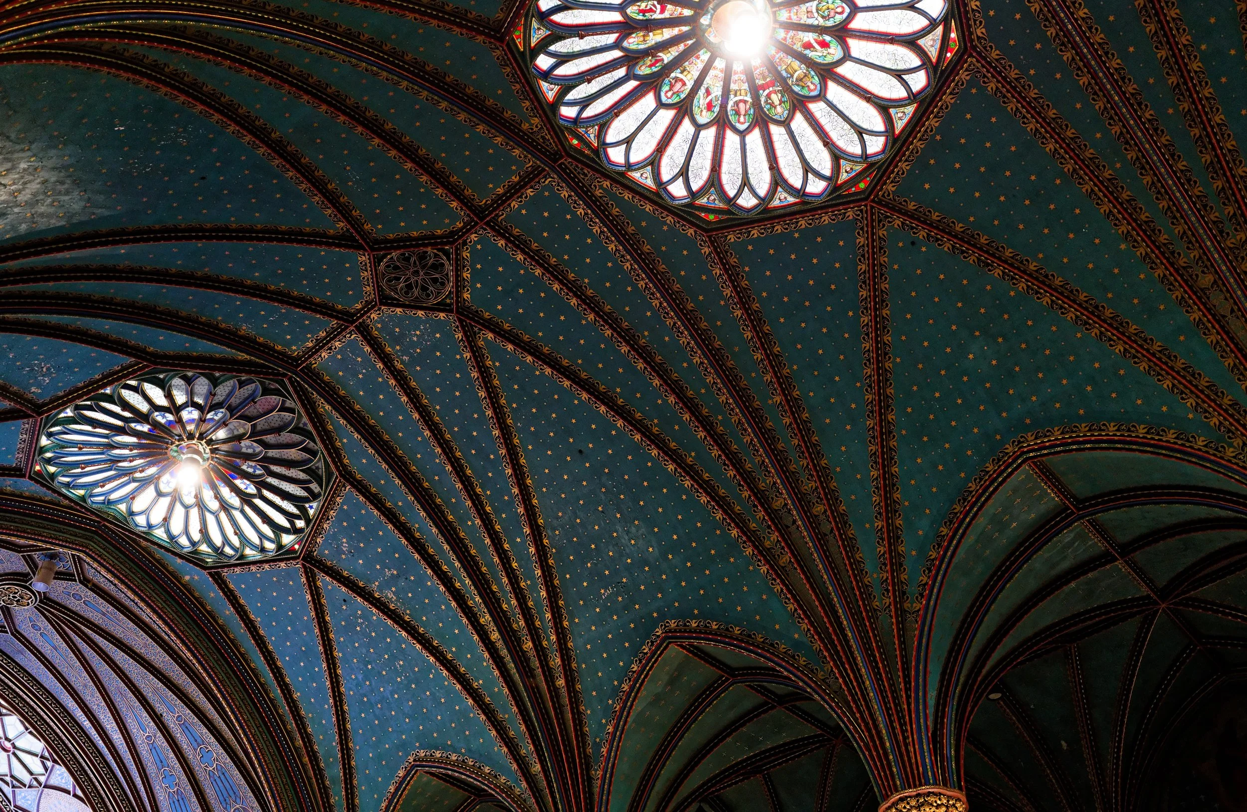 Colorful stained-glass windows and ornate ceiling arches in a cathedral