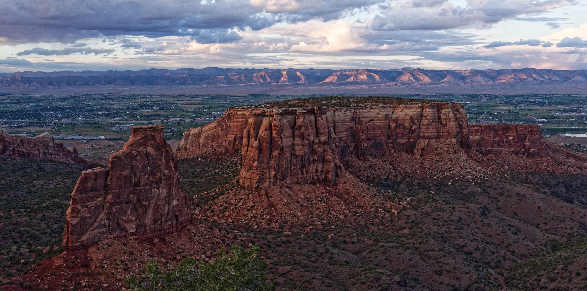 Scenic view of red rock formations and mesa in a desert landscape under cloudy sky.