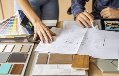 Two people analyzing architectural plans and design samples on a table.