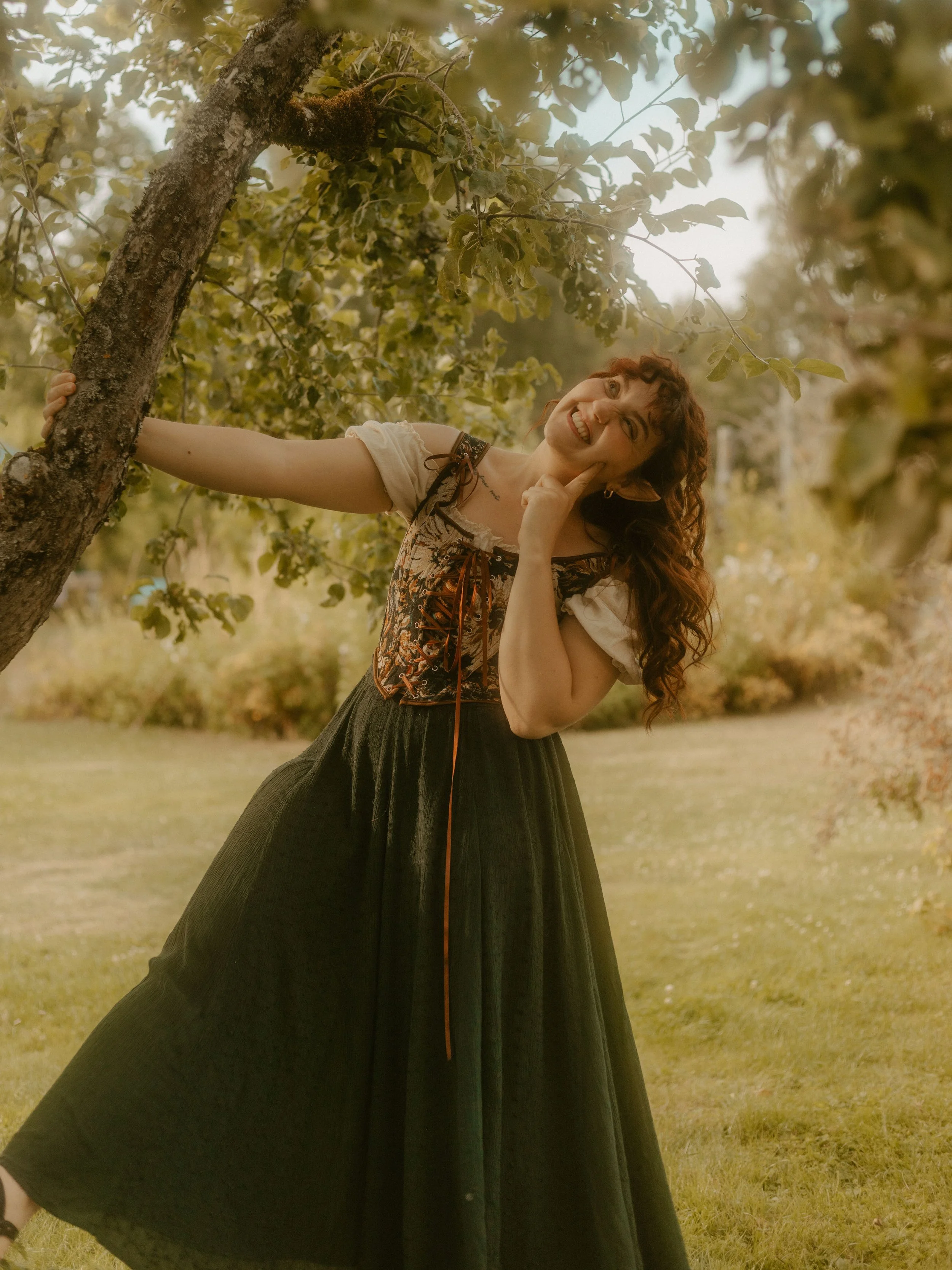 A hobbit woman hanging from a tree branch smiling